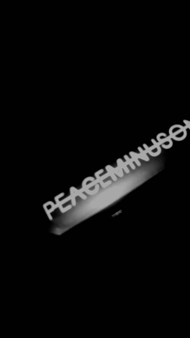 PEACEMINUSONE 美學照片 壁紙 — 一個發光的白色文字 'PEACE MINUS ONE' 以對角線漂浮在純黑色背景上。