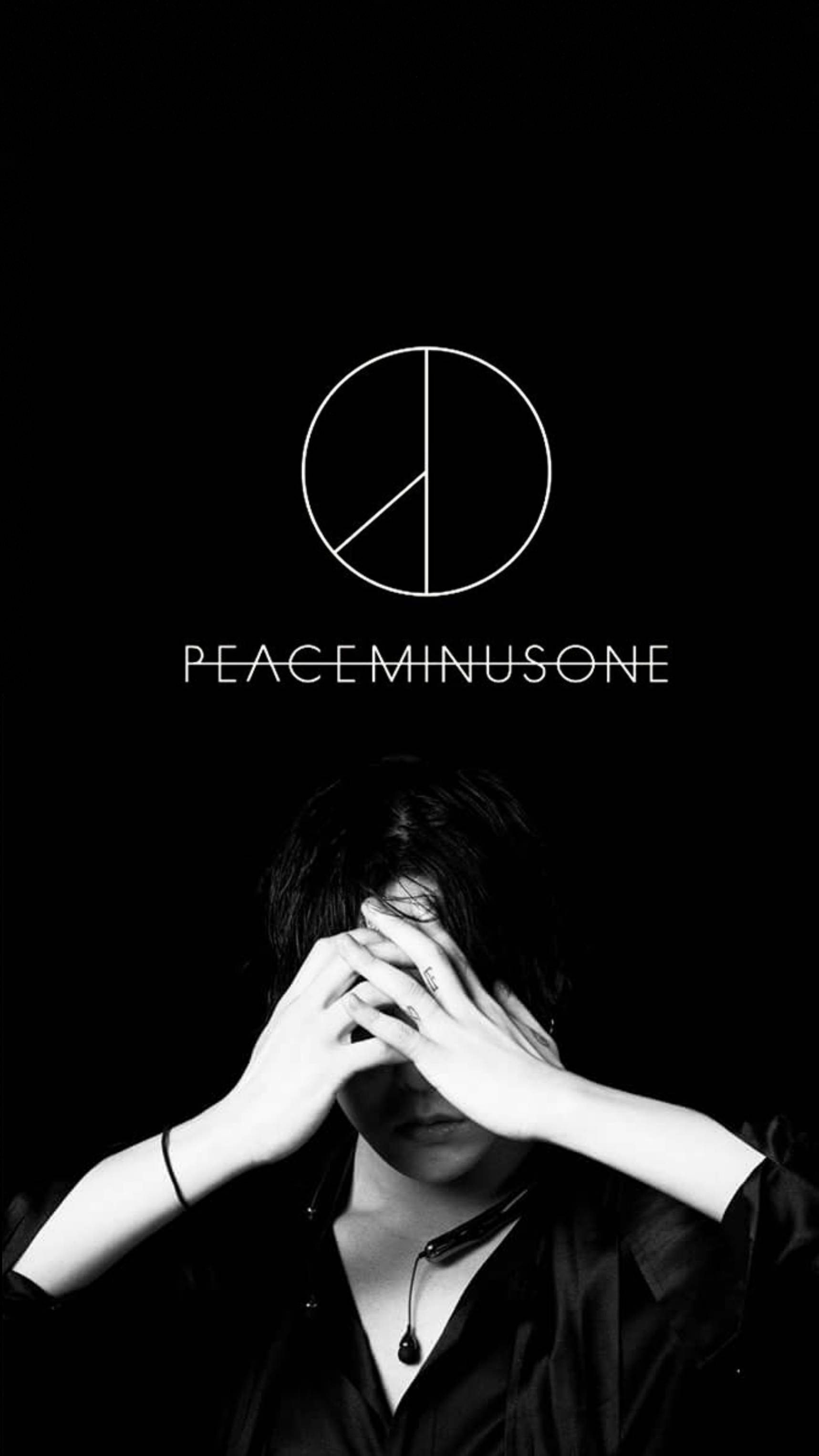 PeaceMinusOne 與 G-Dragon 壁紙 — 一個黑白人物在極簡和平符號標誌下用手遮住臉。