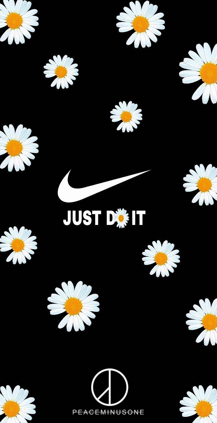 PEACEMINUSONE 與 Nike 壁紙 — 白色雛菊帶黃色花心漂浮在黑色背景上，圍繞著Nike勾勾和「JUST DO IT」標語。