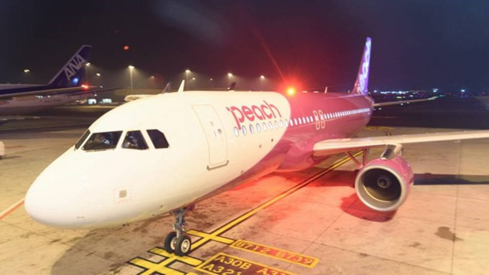Peach Airlines飛機夜間停泊在機場停機坪上，帶有黃色標記。