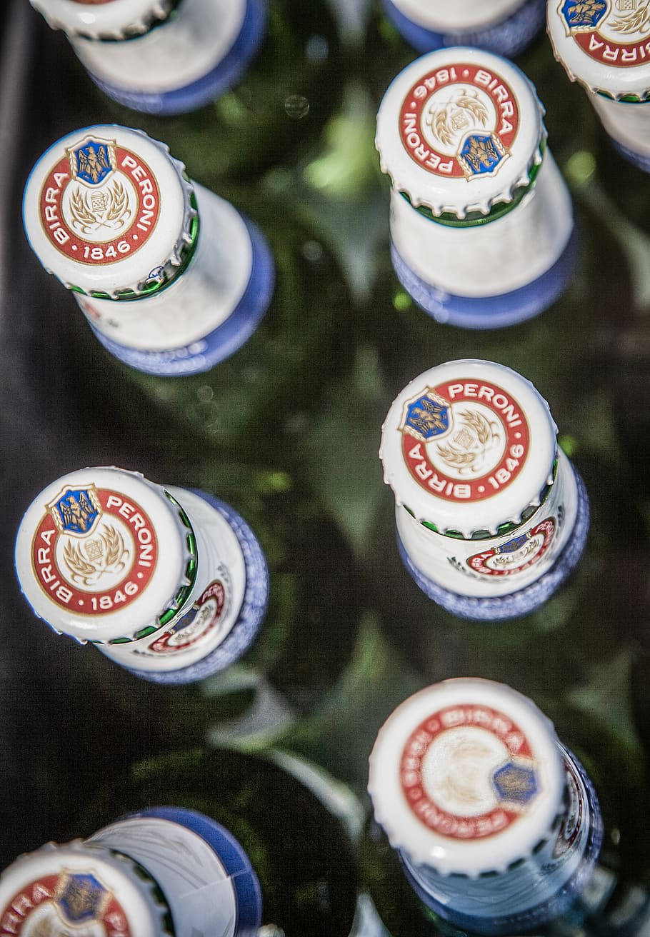 Peroni 啤酒瓶蓋在深色托盤中排列的特寫。