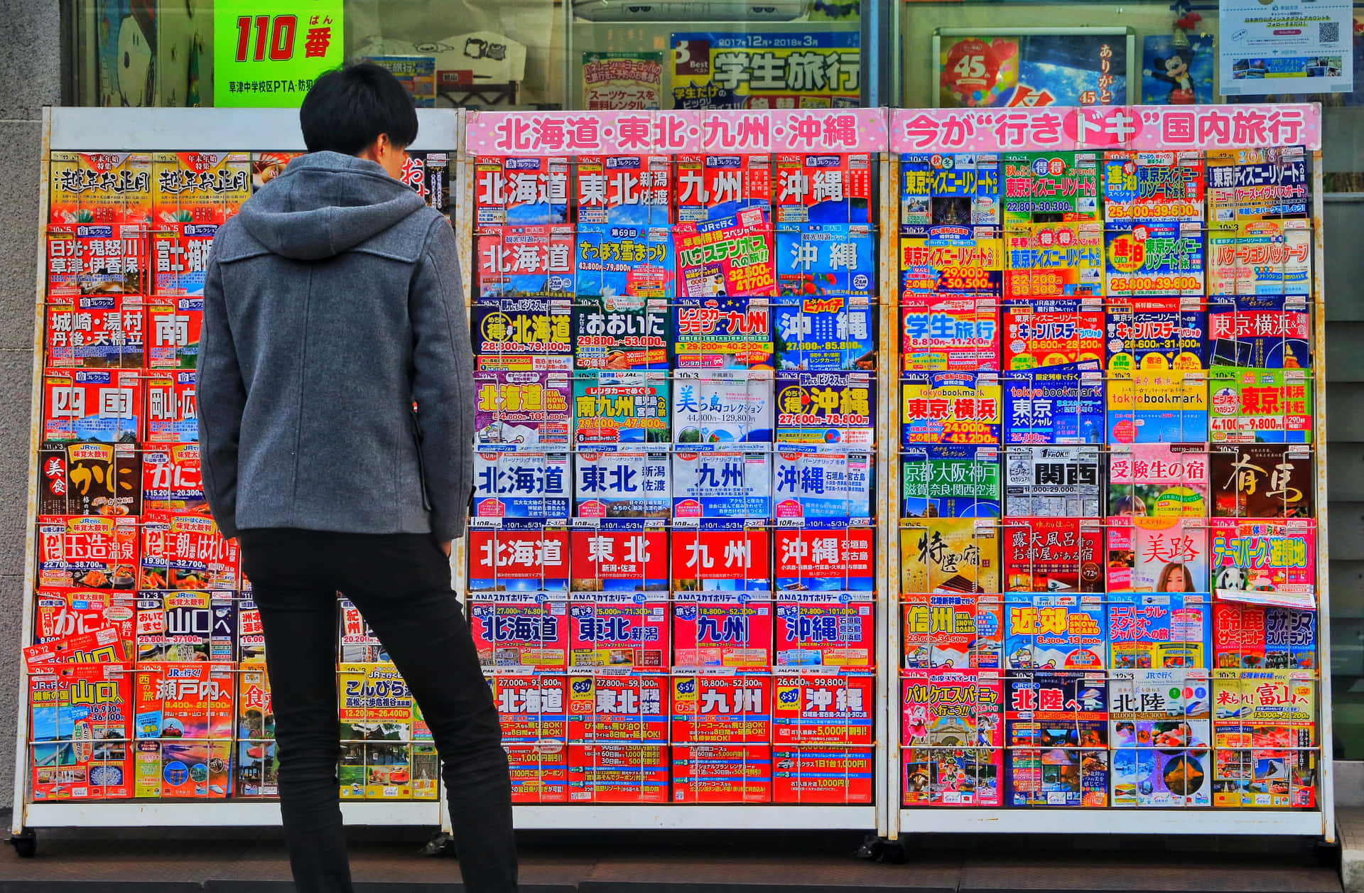 在城市商店櫥窗前瀏覽日本旅遊手冊的人。