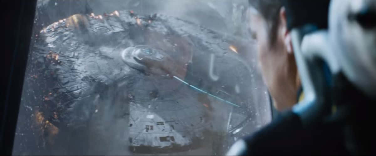 Space Movie 桌布 壁紙 — 一個戴著頭盔的人透過起霧的窗戶凝視著一艘漂浮在太空中、帶有熊熊火焰的巨大受損太空船。