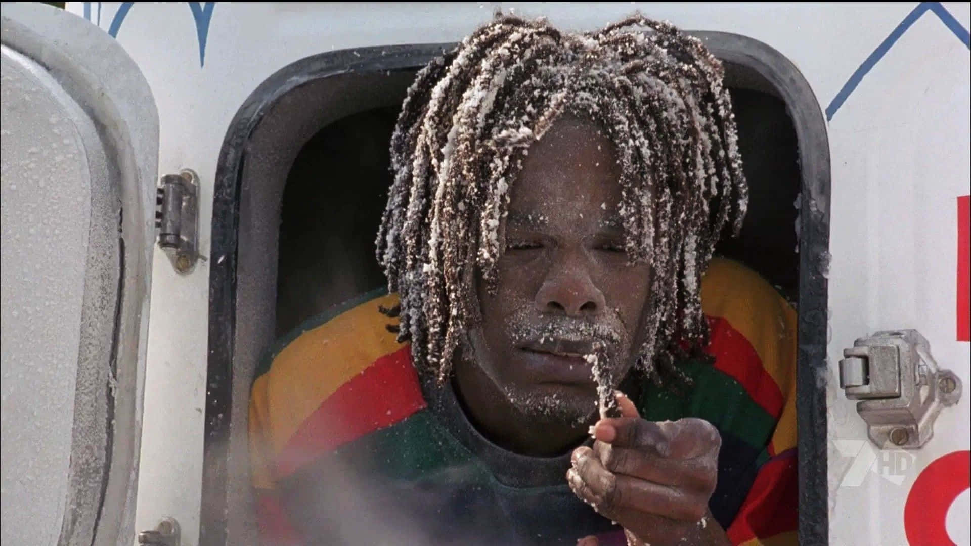  壁紙 — 一個頭戴雪覆蓋的辮子的人從車窗探出頭來，手裡拿著一片雪花。
