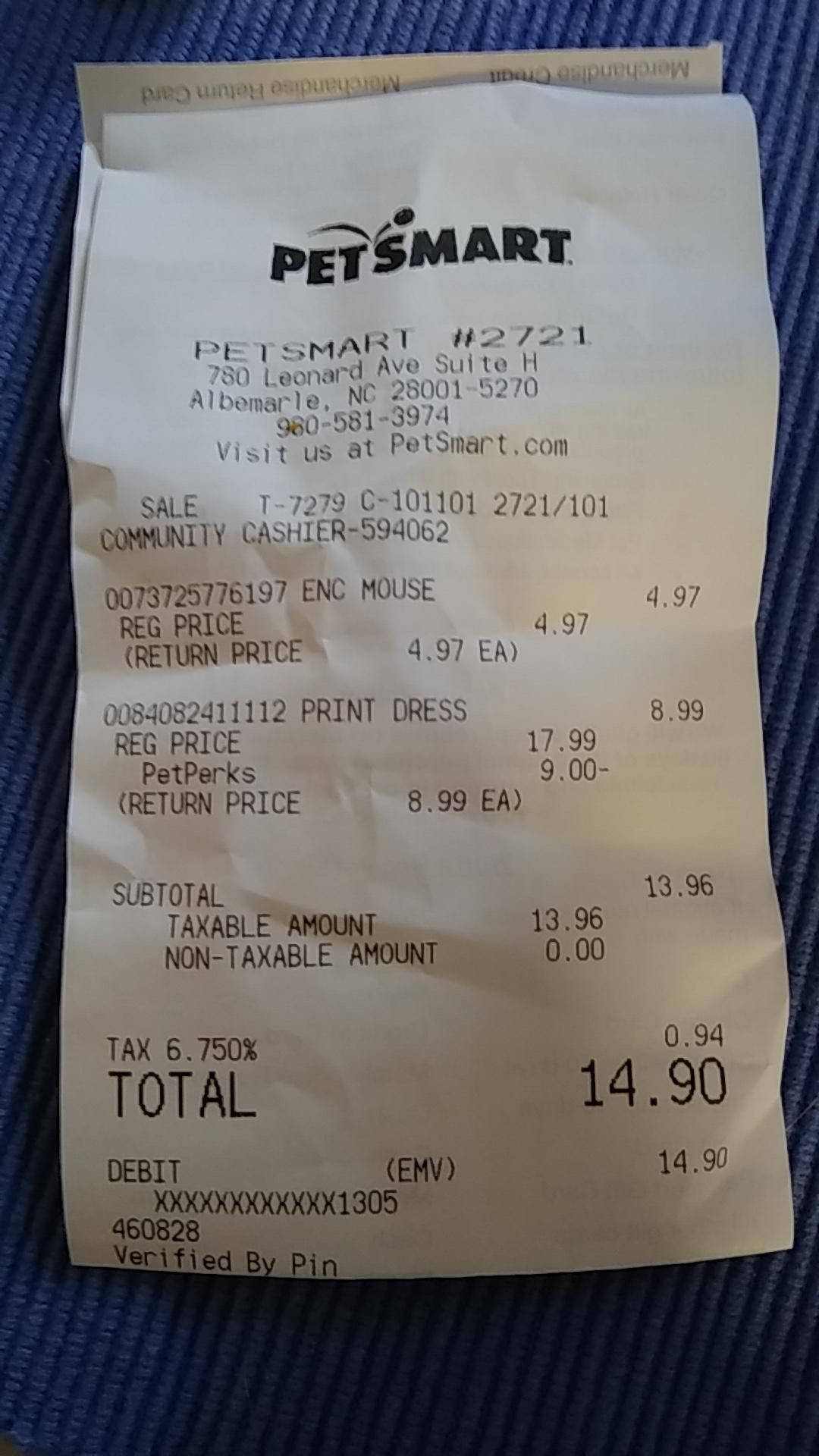 PetSmart收據特寫 壁紙 — 一張皺巴巴的 PetSmart 收據，列出退貨商品和總金額，放在有紋理的藍色布料表面上。