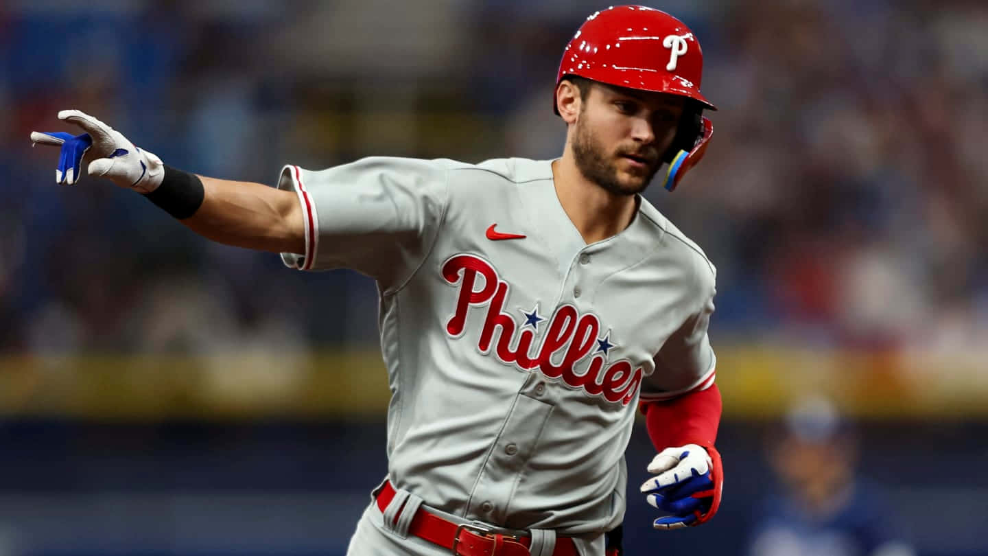 Trea Turner Phillies 桌布 壁紙 — 一名費城費城人棒球選手穿著灰色球衣，在夜間比賽的球場燈光下專注地奔跑。