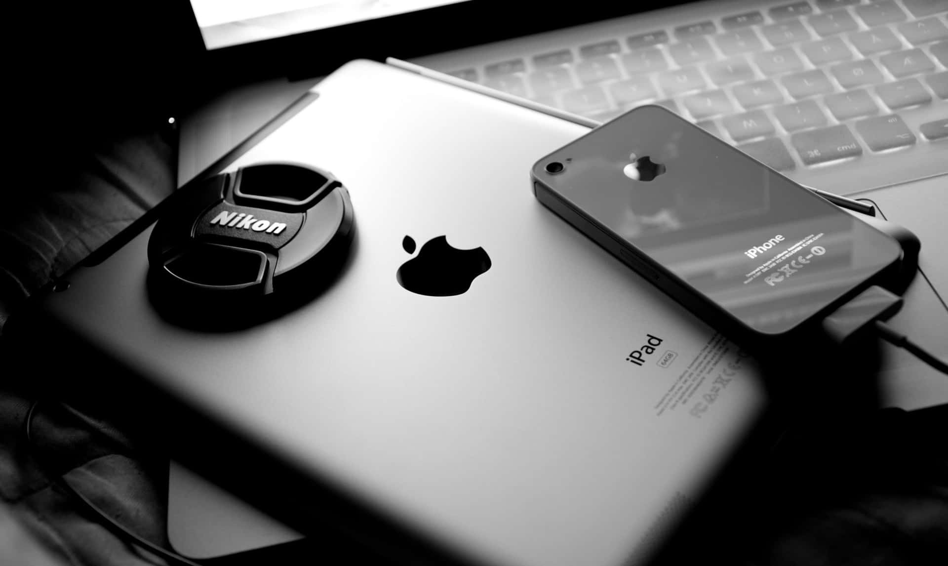 桌上科技產品的黑白照片，包括iPad、iPhone和手提電腦。