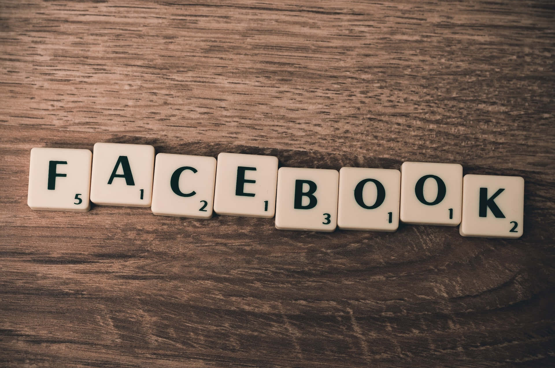 Video Marketing 桌布 壁紙 — 拼出 facebook 的 Scrabble 字母牌放在有紋理的木質表面上，帶有溫暖的復古色調。