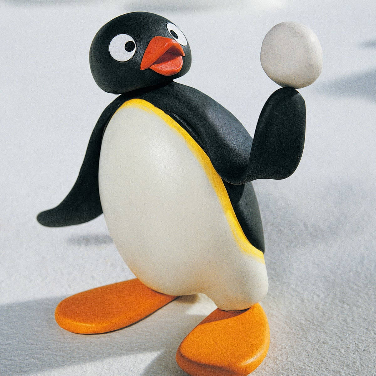 Pingu 手持雪球 壁紙 — 一個迷人的黏土企鵝公仔，有橙色喙和腳，在雪景背景下拿著雪球。