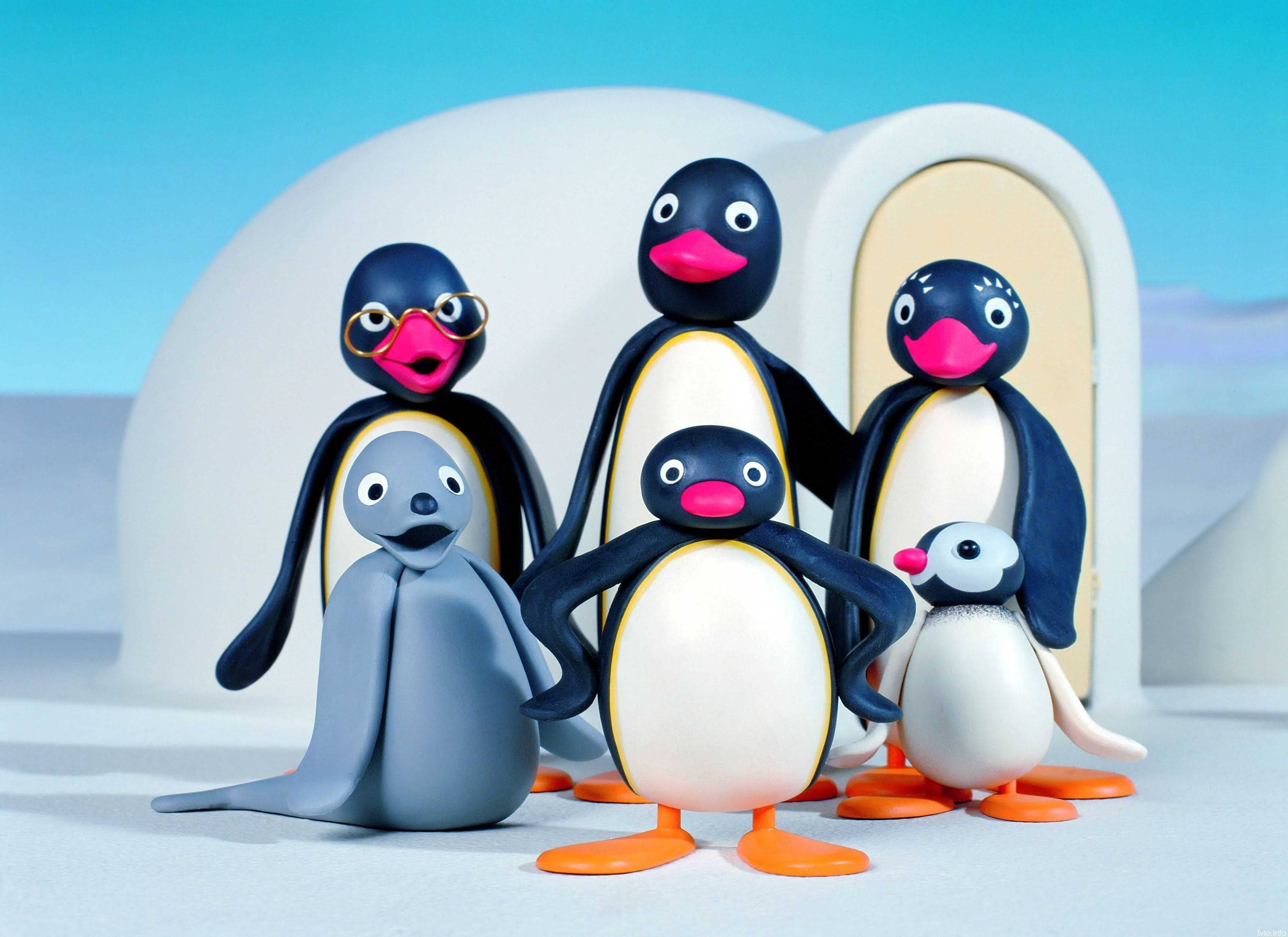Pingu 與家人 壁紙 — 一群色彩繽紛的黏土企鵝家庭和一隻海豹一起站在冰屋前，背景是明亮的藍天。