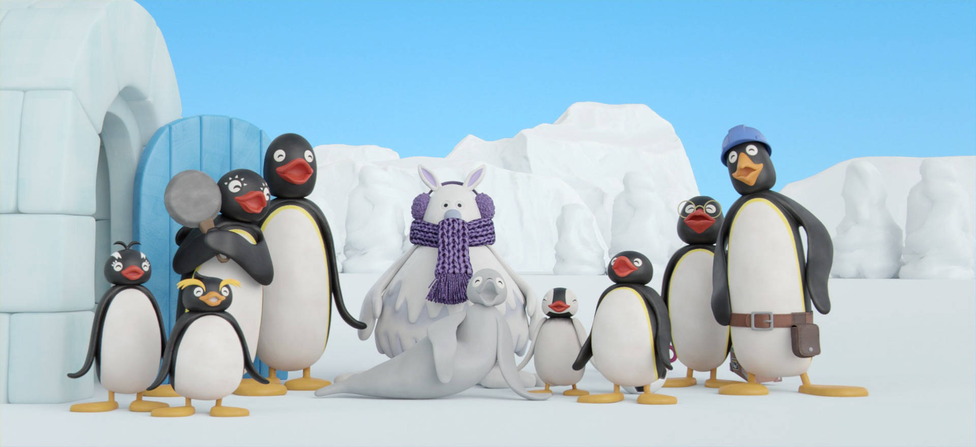 Pingu 與家人和朋友 壁紙 — 一群歡樂的動畫企鵝和海豹在晴朗藍天下白雪覆蓋的冰屋村莊中。