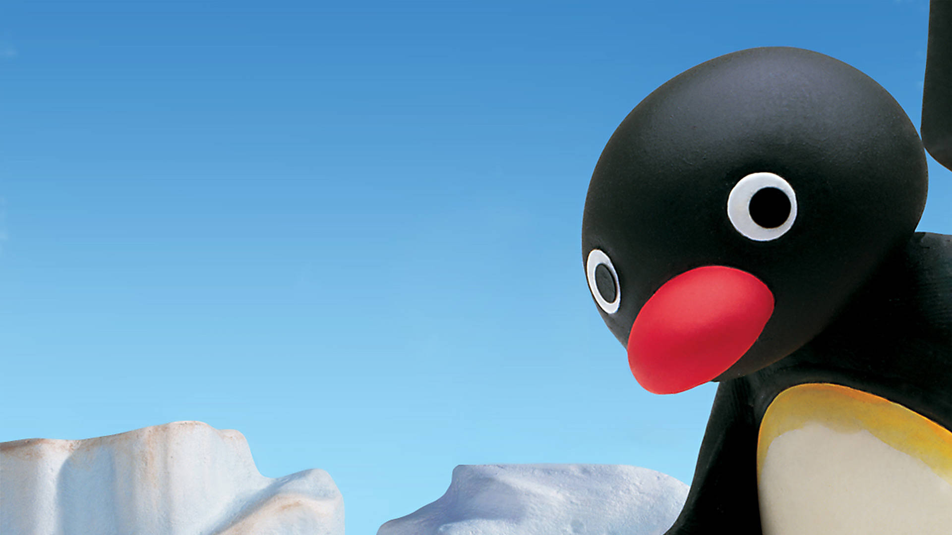 Pingu從螢幕右側偷窺 壁紙 — 動畫企鵝Pingu嘅特寫，企喺雪冰上，背景係晴朗藍天。