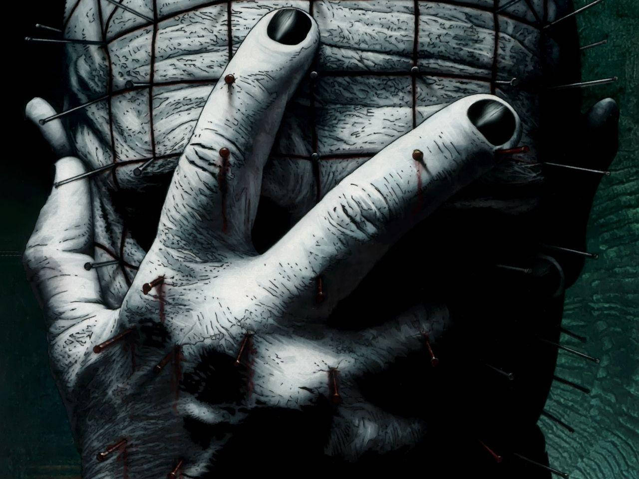 Pinhead 痛苦之王 壁紙 — 恐怖主題特寫，一隻蒼白、佈滿大頭針的手抓住金屬網罩在臉上，指甲滴著血。