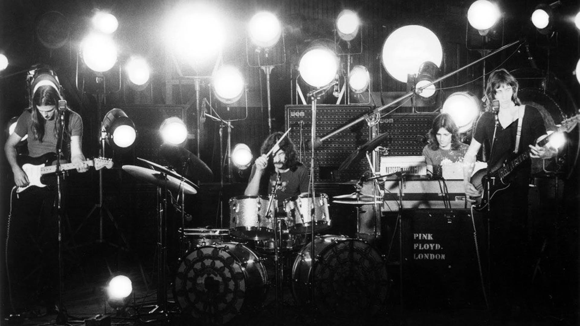 Pink Floyd 樂隊在明亮的燈光下在舞台上現場表演。