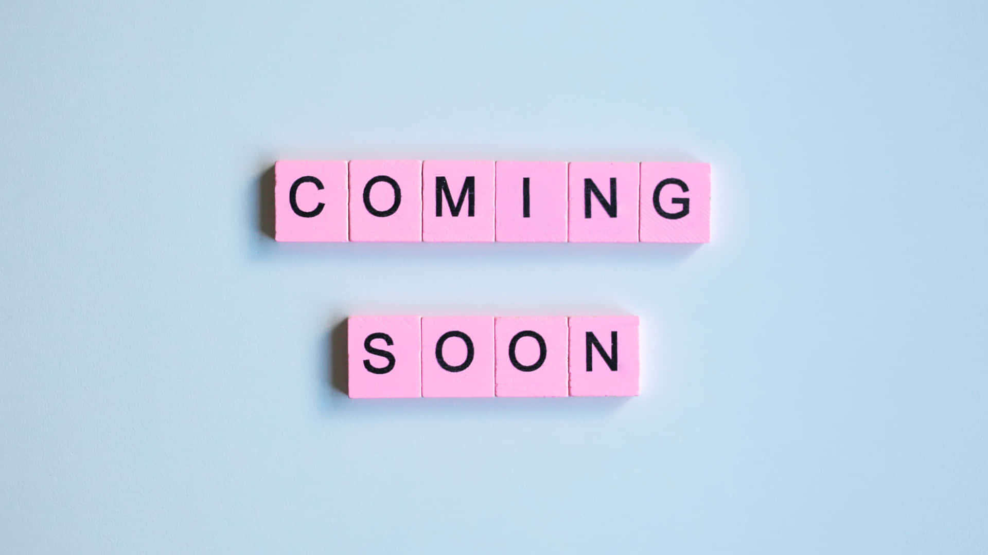 粉紅色瓷磚在藍色表面上拼出「coming soon」。