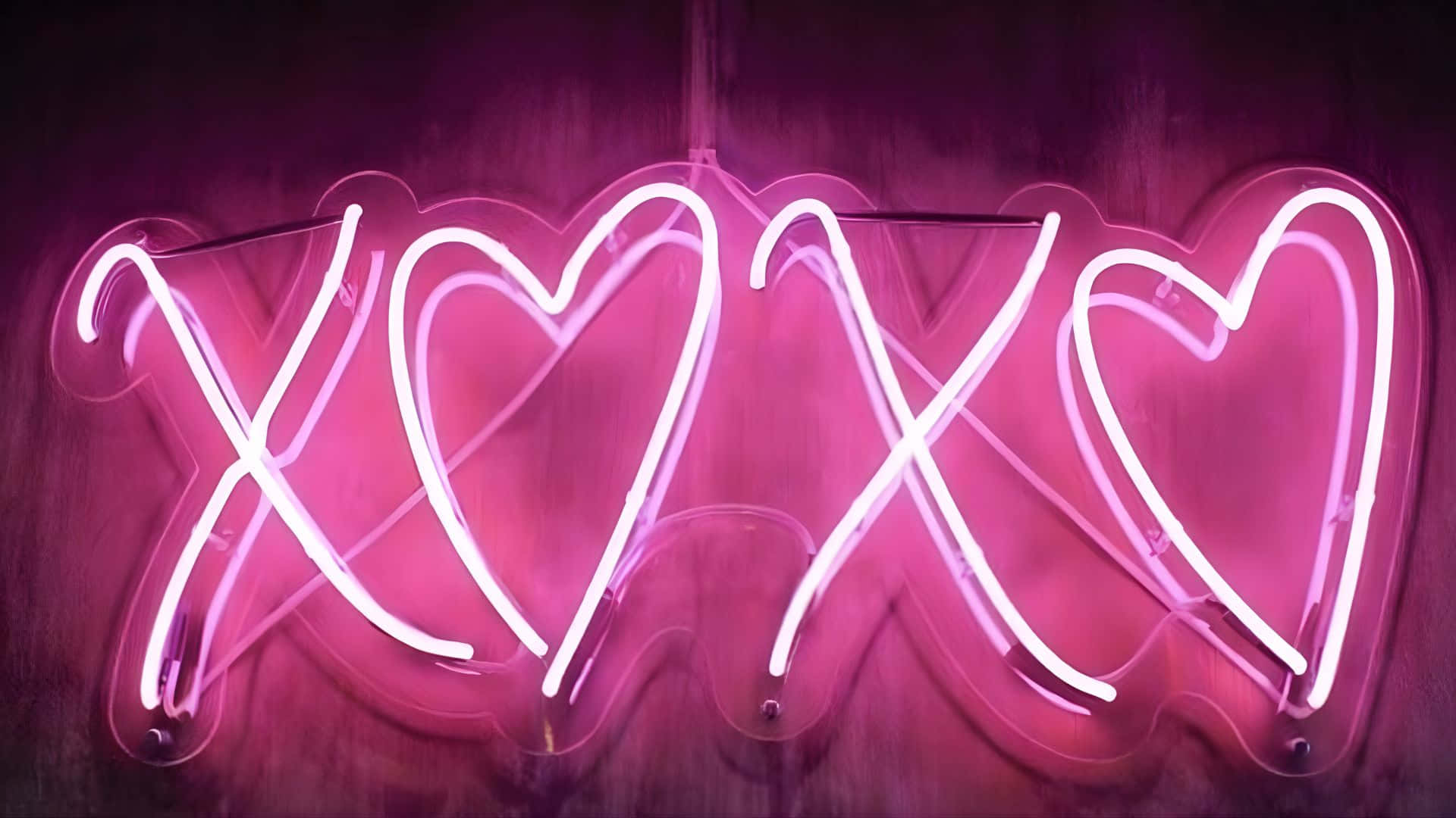  壁紙 — 一個發光的粉紅色霓虹燈牌，以心形拼出「XOXO」，在深色木牆上投射出浪漫的光芒。