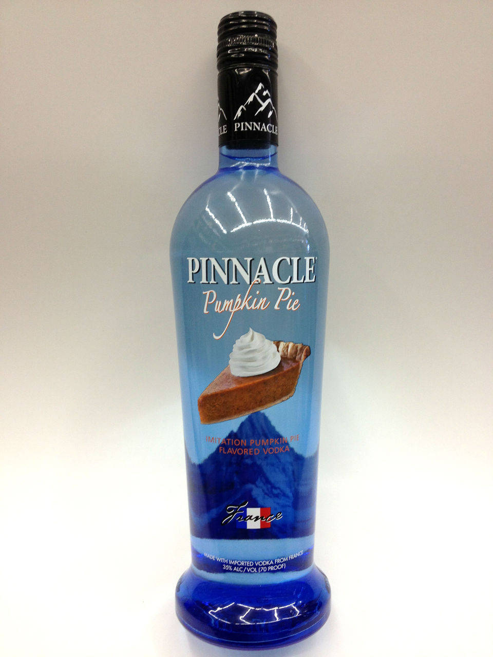 白色背景上的Pinnacle Pumpkin Pie味伏特加酒藍色樽。