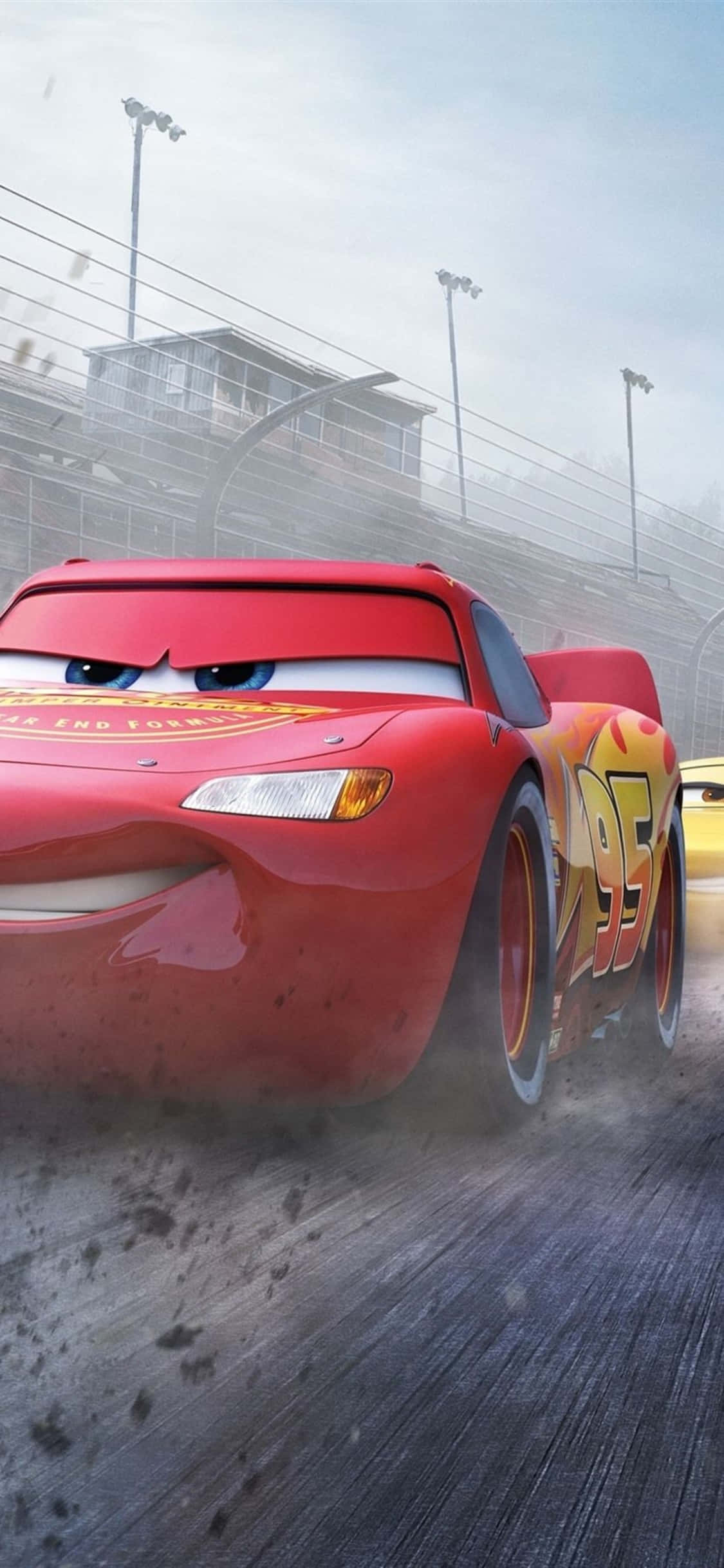 Piston Cup 賽車 iPhone X 賽車壁紙 壁紙 — 一輛紅色動畫賽車，編號95，在塵土飛揚的賽道上疾馳，背景是體育場燈光。