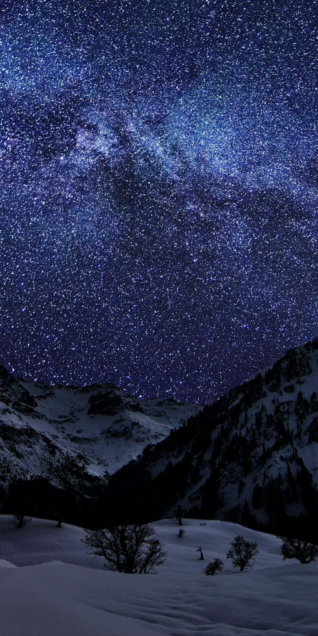 Pixel 3 冬日背景：雪山與繁星夜空 壁紙 — 在深藍色夜空下，銀河系橫跨積雪的山峰，景色令人嘆為觀止。
