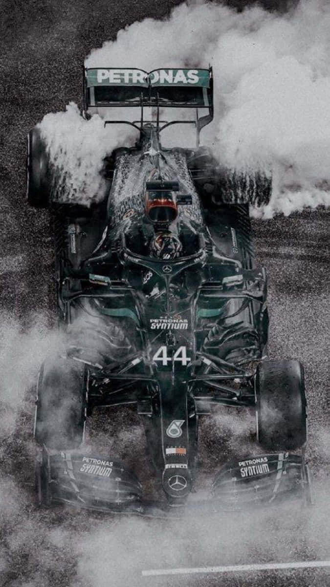 在 Pixel 3 上衝向「Grid Autosport」的終點線 壁紙 — 一輛帶有44號和Petronas標誌的一級方程式賽車在潮濕的賽道上飛馳，戲劇性地冒煙。