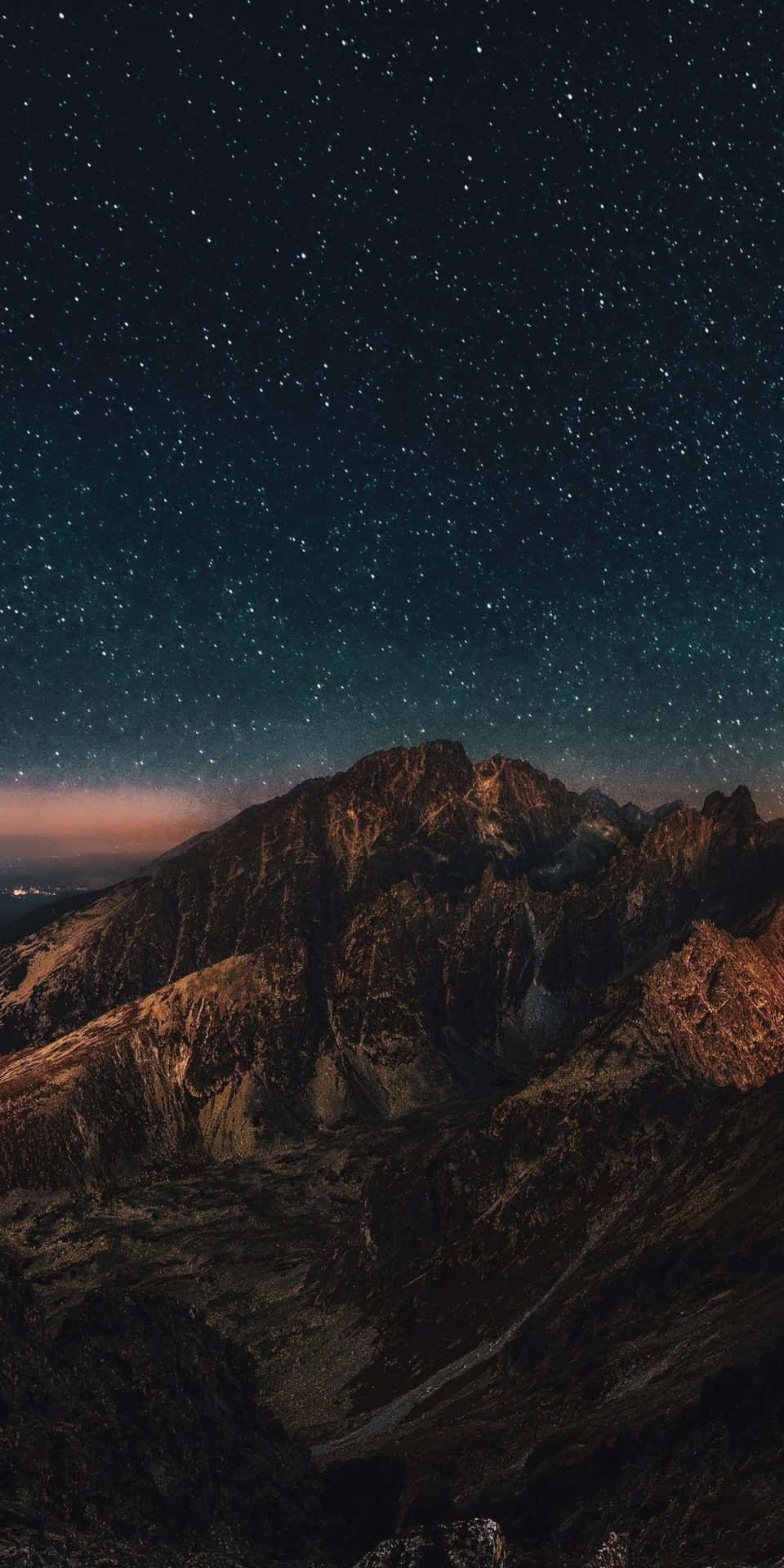繁星點點的夜空在崎嶇的山峰之上，發光的地平線。