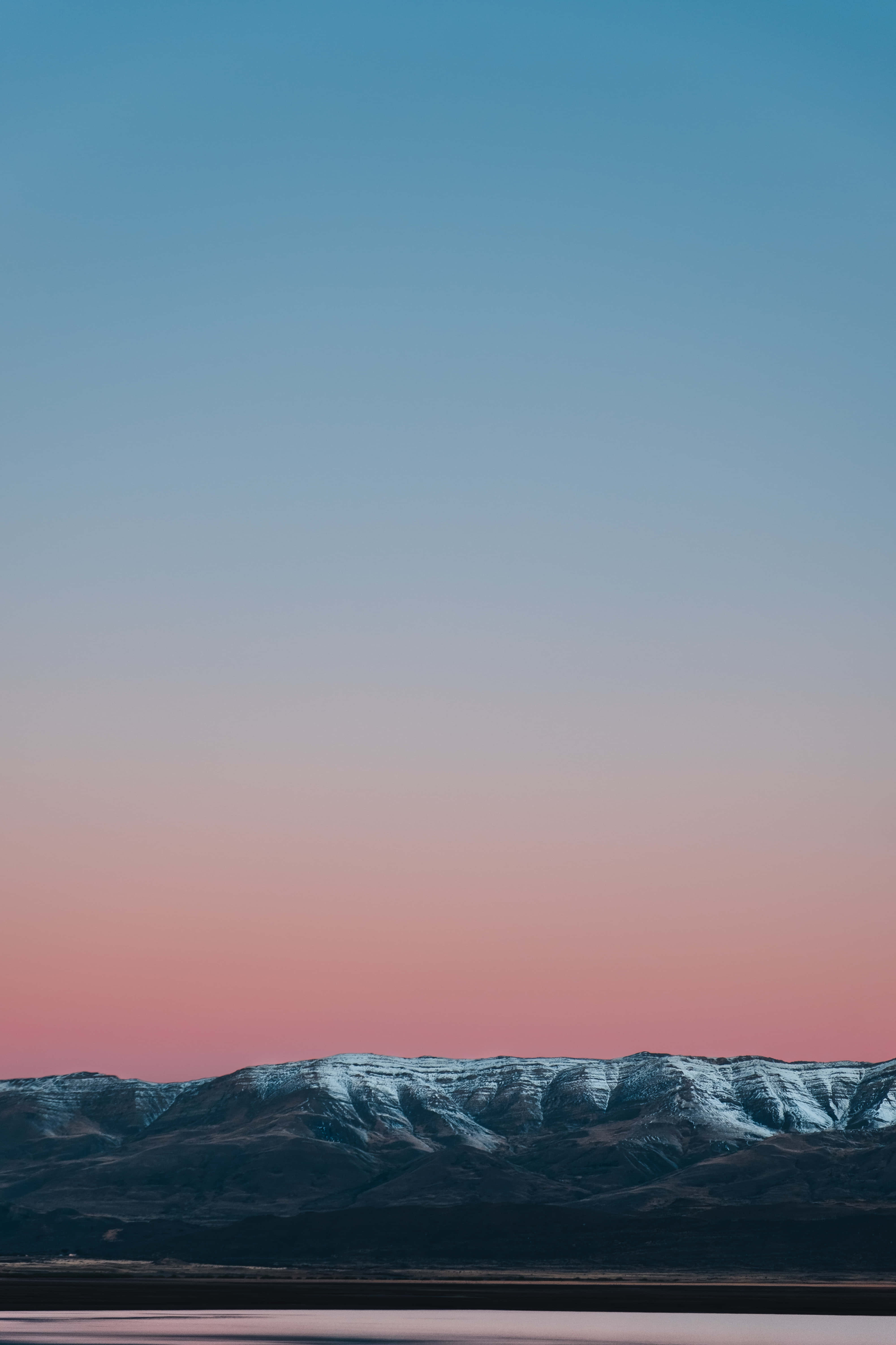 Pixel 3 與 Apple 壁紙 — 黃昏時分，白雪覆蓋的山峰在藍粉漸變的天空中形成剪影。