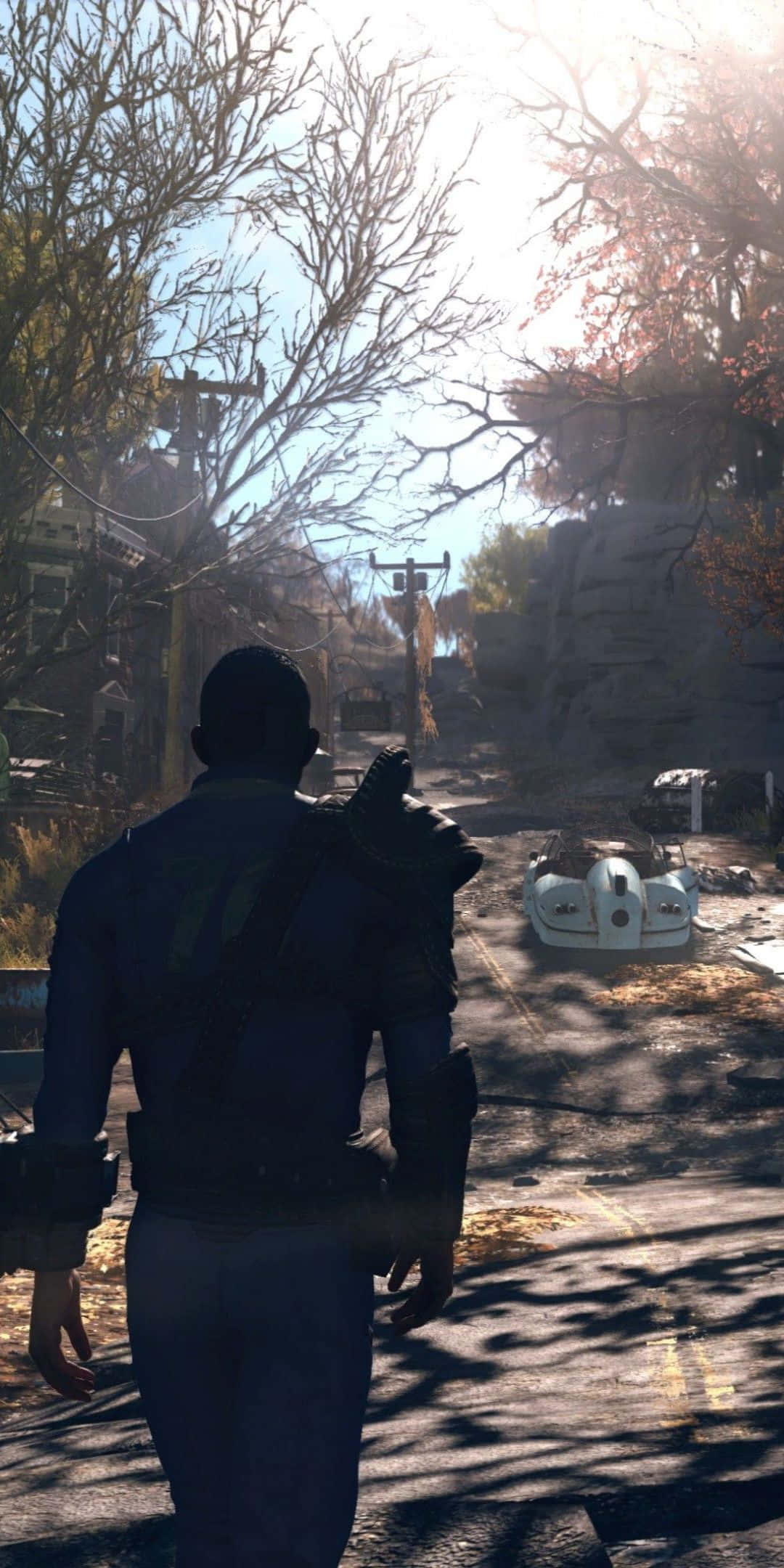 Pixel 3 與 Fallout 76 — 震撼遊戲組合 壁紙 — 一個孤獨的倖存者走過一個陽光明媚、雜草叢生的末日後荒原，到處是枯樹和廢棄車輛。