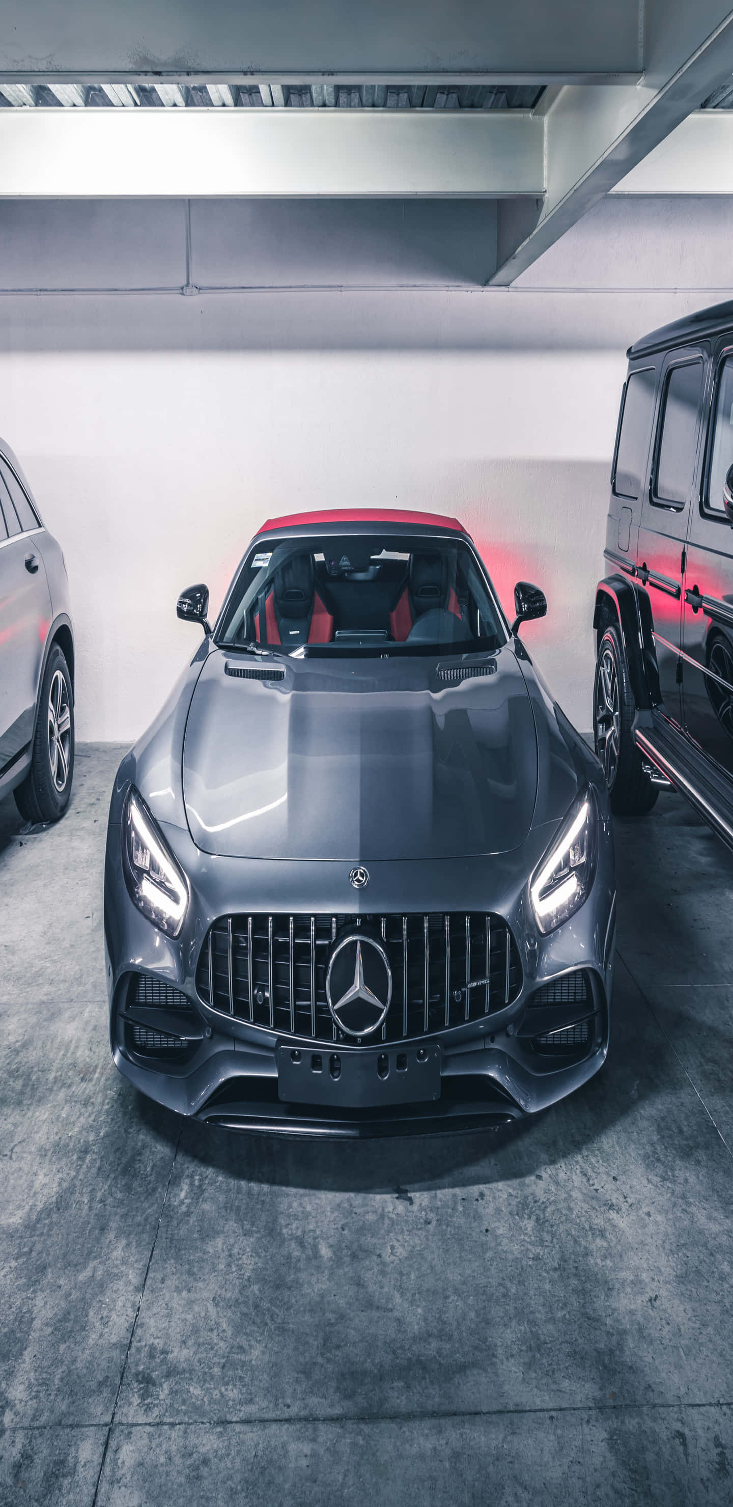 震撼 Pixel 3XL AMG GT-R 背景 壁紙 — 一架時尚的灰色 Mercedes-AMG 跑車帶有紅色點綴，停泊在現代車庫中，旁邊是一輛黑色 SUV。