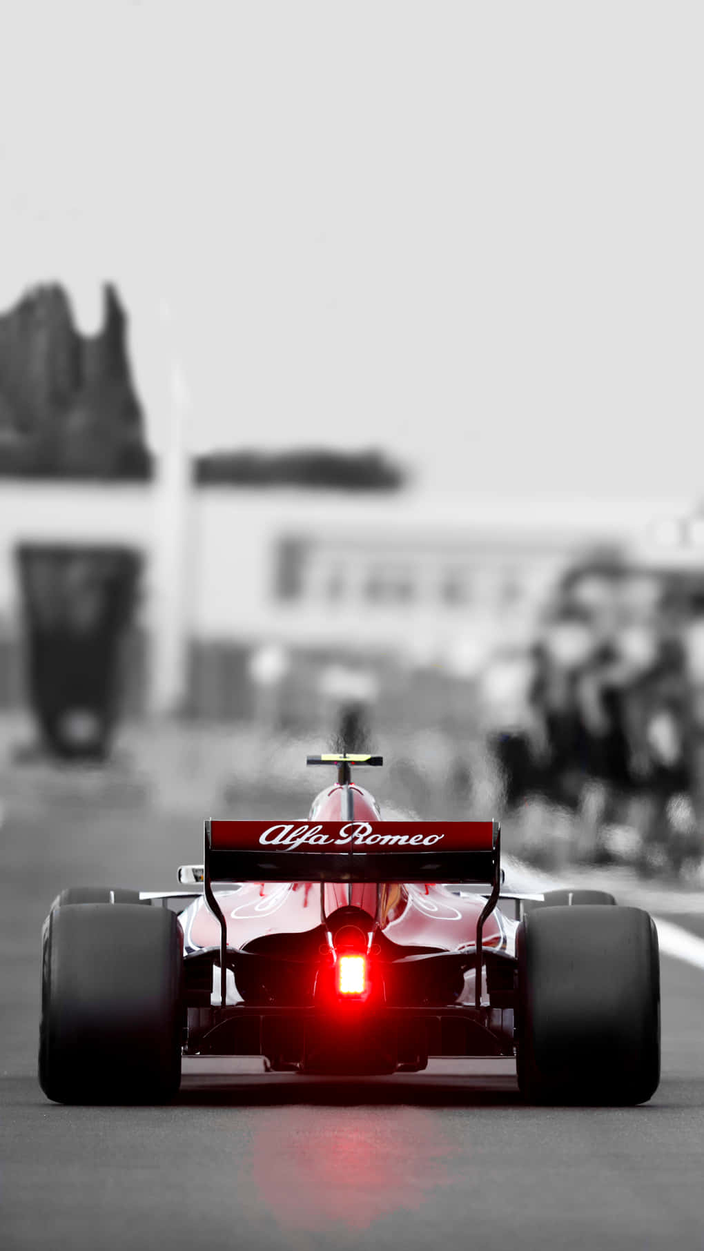 紅色愛快羅密歐F1賽車在賽道上疾馳，尾燈發光。