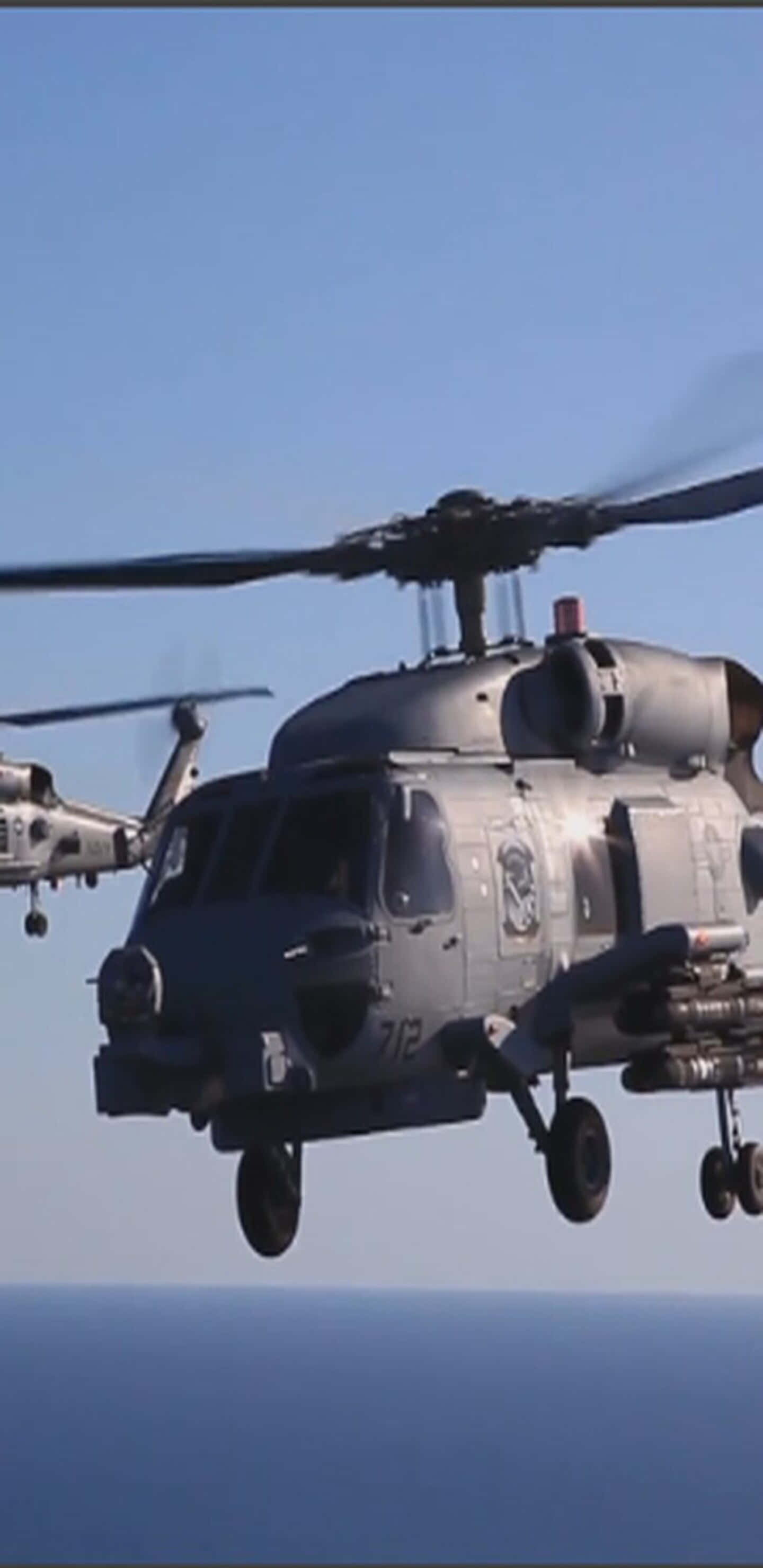 Pixel 3XL 直升機背景 Sikorsky SH-60 Seahawk 壁紙 — 兩架灰色軍用直升機在晴朗天空下低飛過平靜的藍色海洋。
