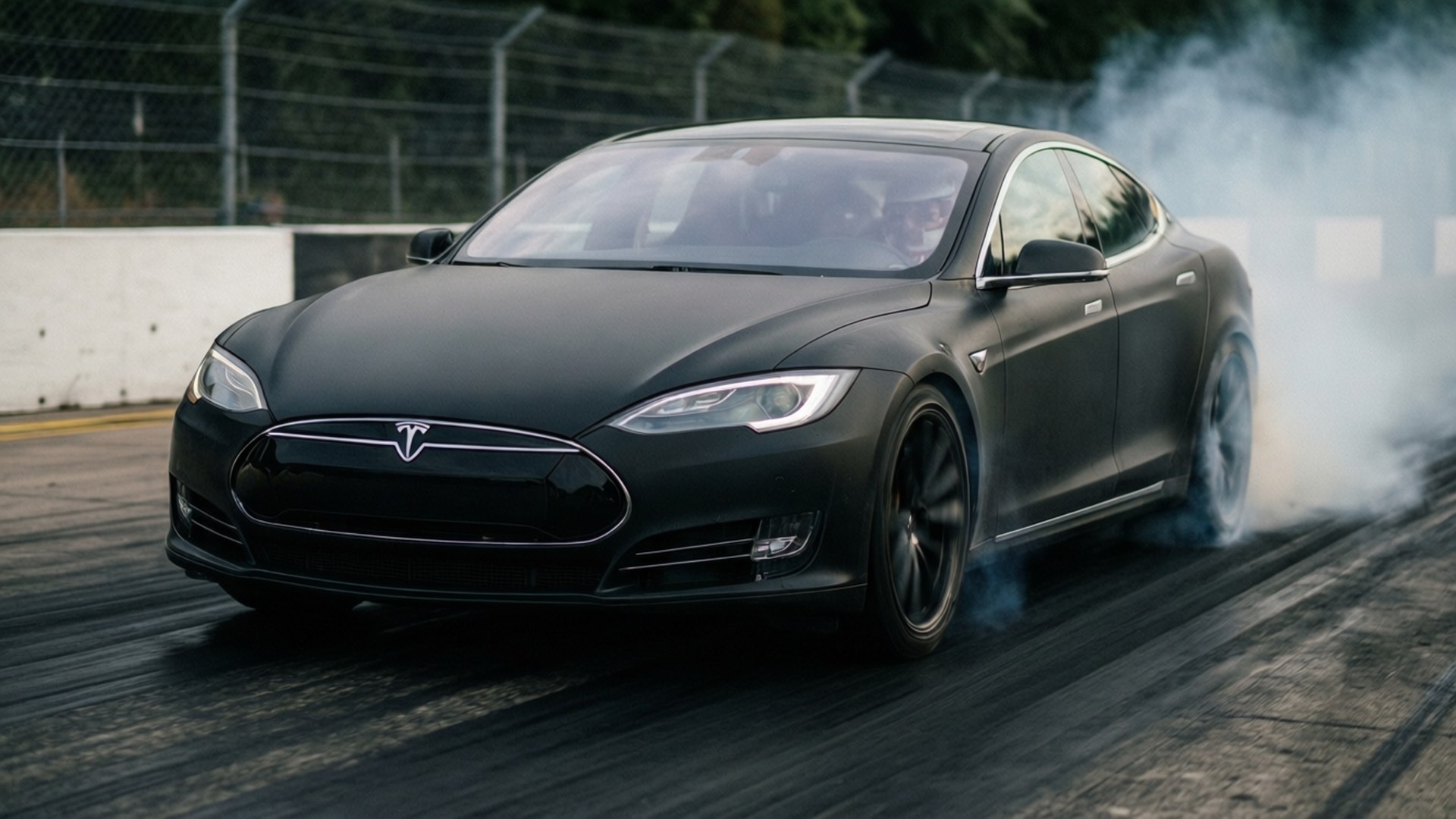 黑色Tesla Model S在賽道上飄移，輪胎冒煙