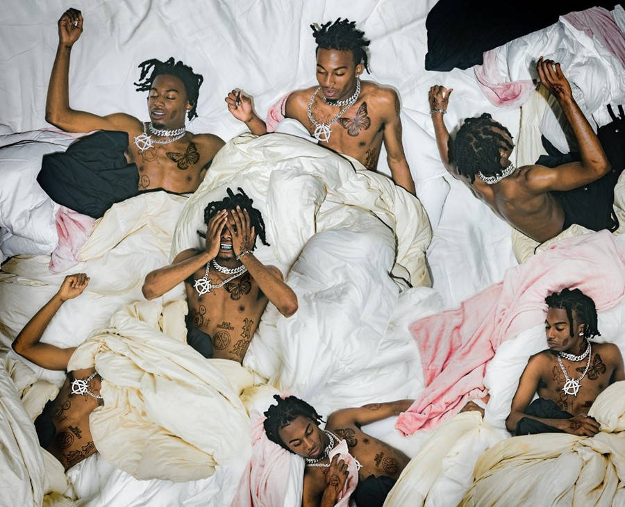 Playboi Carti PFP 躺在床上 壁紙 — 六個赤膊紋身男子戴著鎖鏈，戲劇性地攤在凌亂的白色和粉紅色床單上，構成混亂的臥室場景。