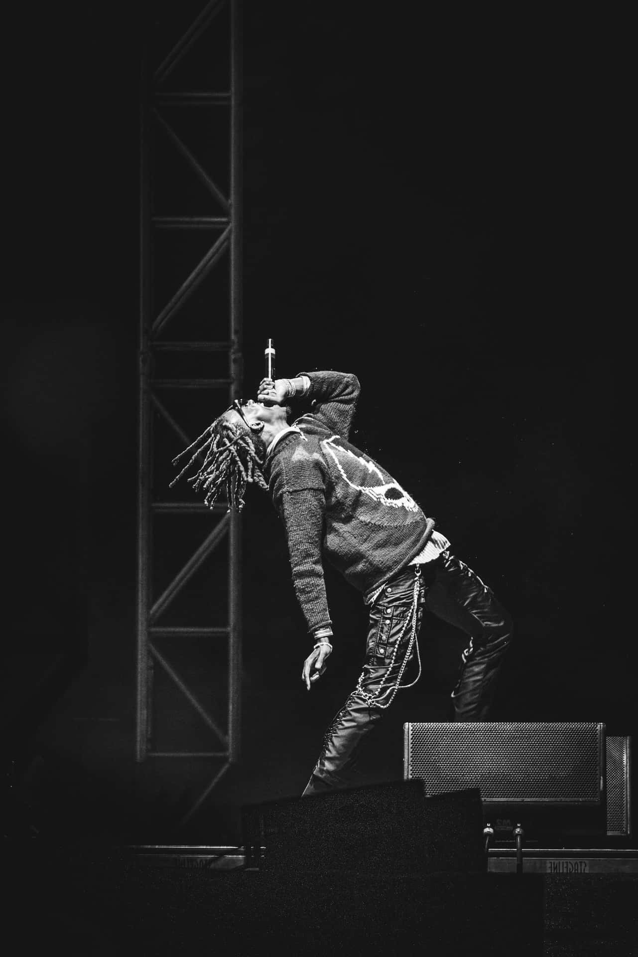 一位留著辮子的音樂家在戲劇性燈光下於舞台上表演。
