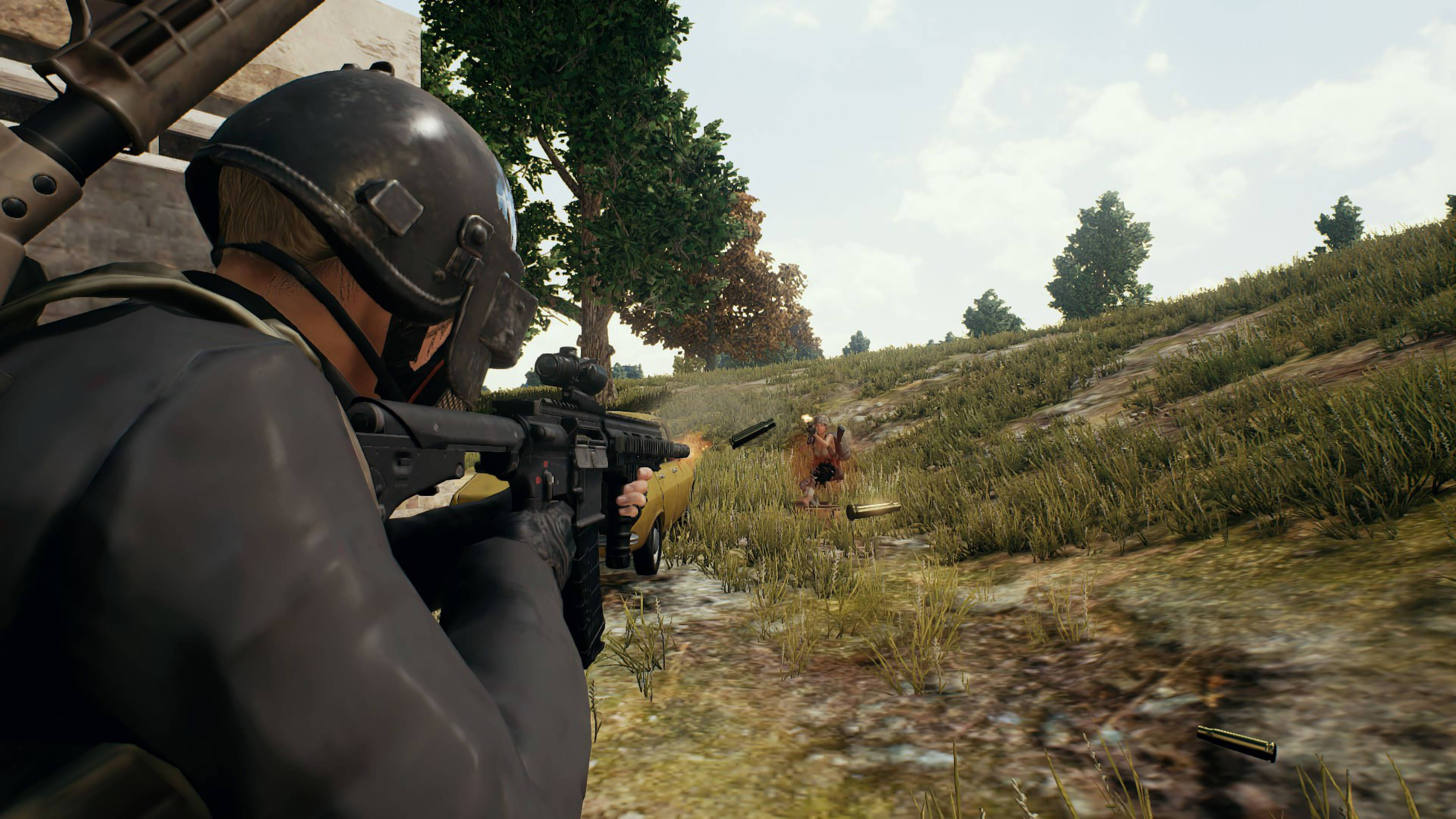 《Playerunknown's Battlegrounds》4K – 專業級遊戲畫面 壁紙 — 一名身穿戰術裝備的士兵在草地上散落著彈殼的戶外戰場上，用步槍瞄準敵人。