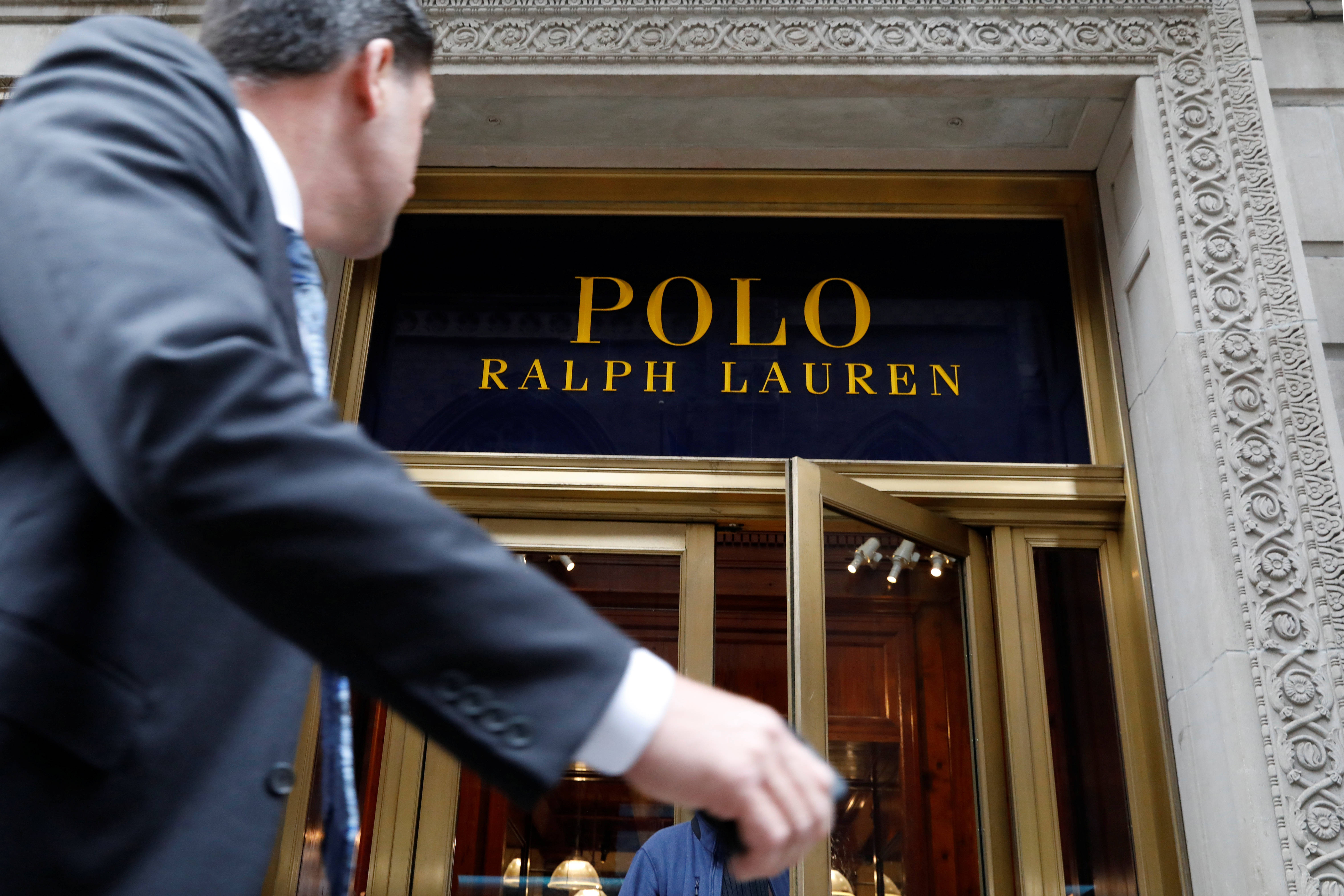 Polo Ralph Lauren 入口 壁紙 — 一名身穿西裝的男子走過Ralph Lauren商店華麗的入口，入口處有金色字體和精緻的石頭建築。