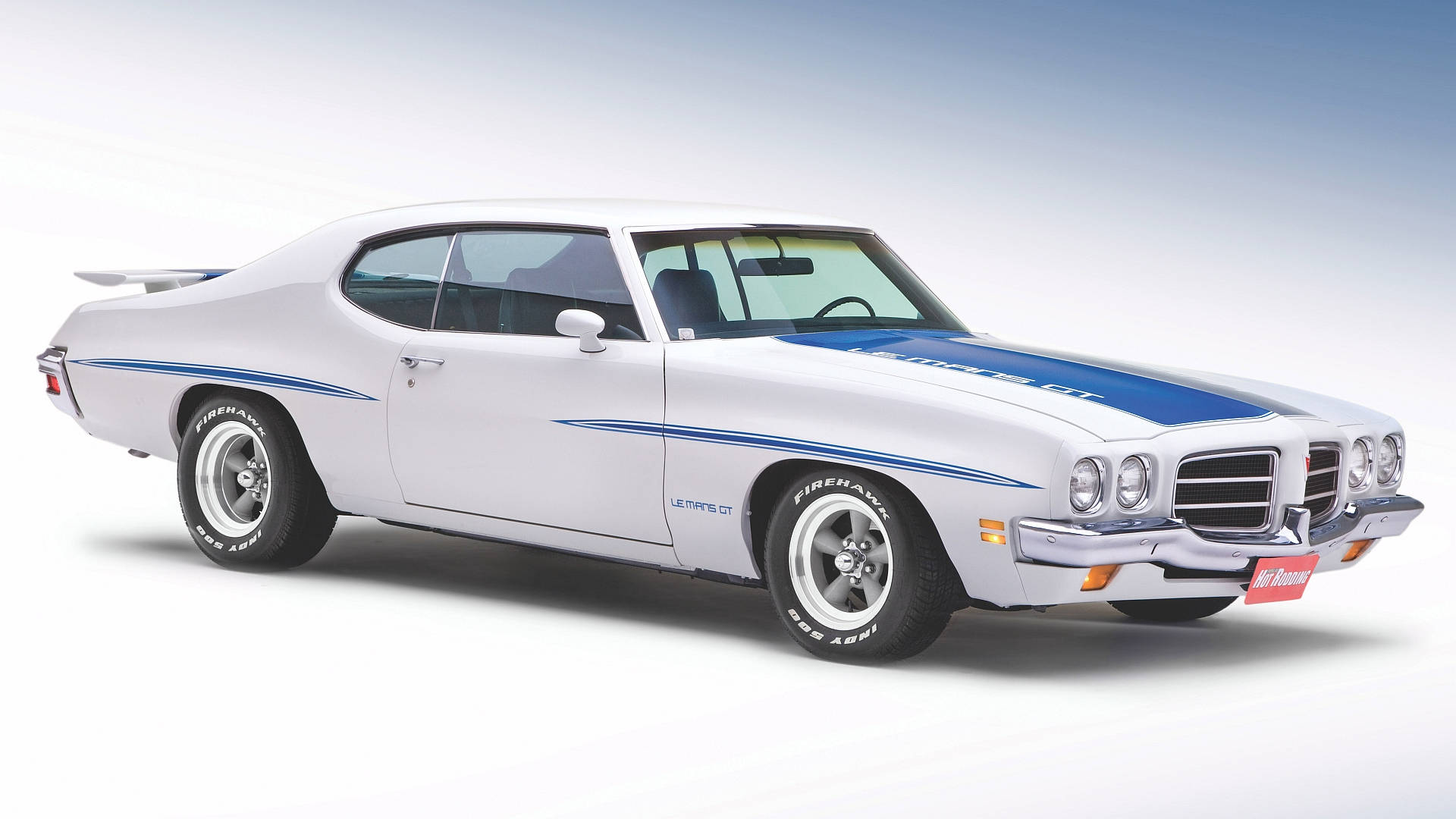 Pontiac LeMans 白色車款 壁紙 — 一輛純白色的經典肌肉車，帶有醒目的藍色賽車條紋，在漸變天空背景下的攝影棚燈光中閃耀。