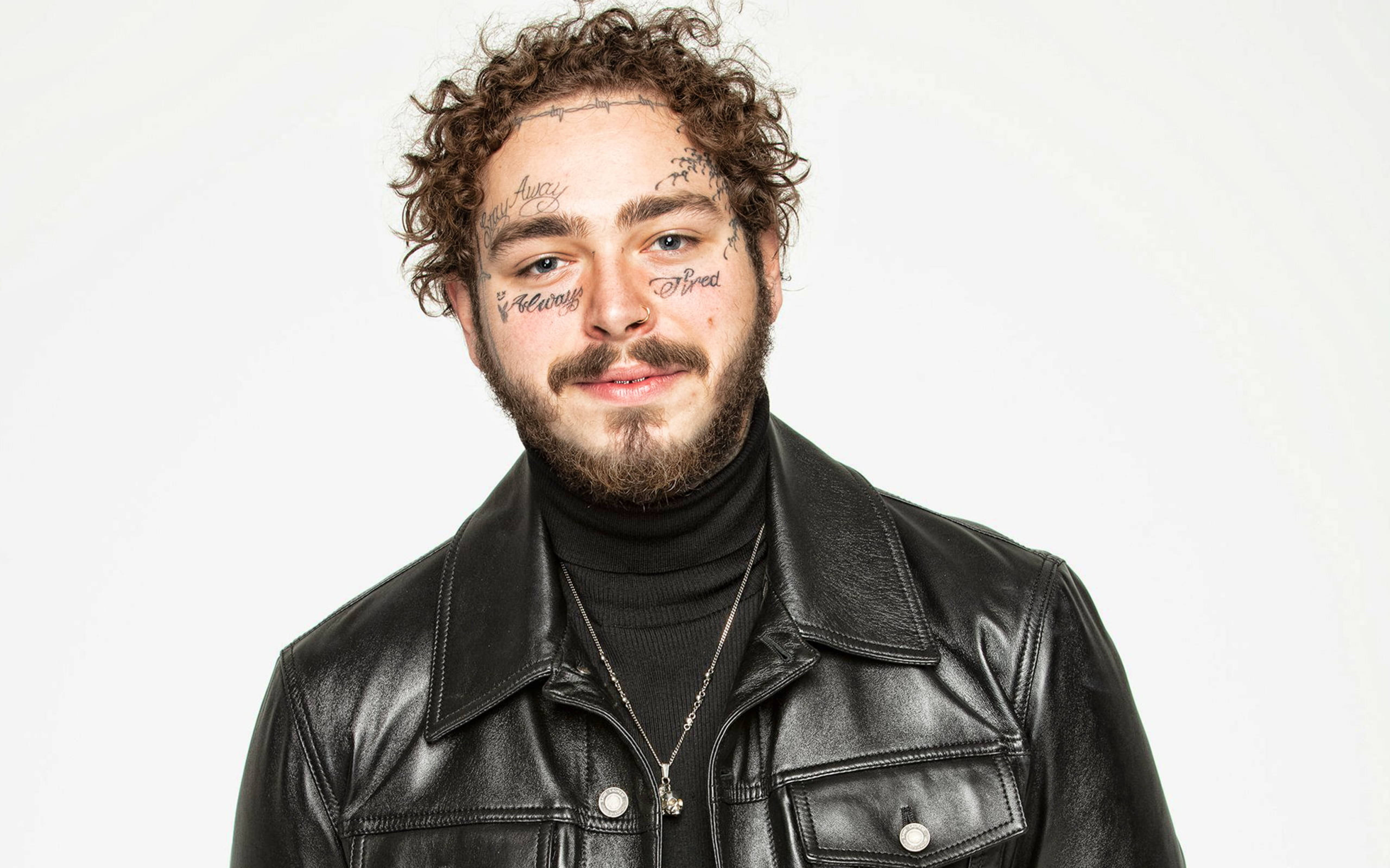 Post Malone HyperX大使形象 壁紙 — 一個有捲髮和臉部紋身的男人，在純白色背景前穿著黑色皮夾克。