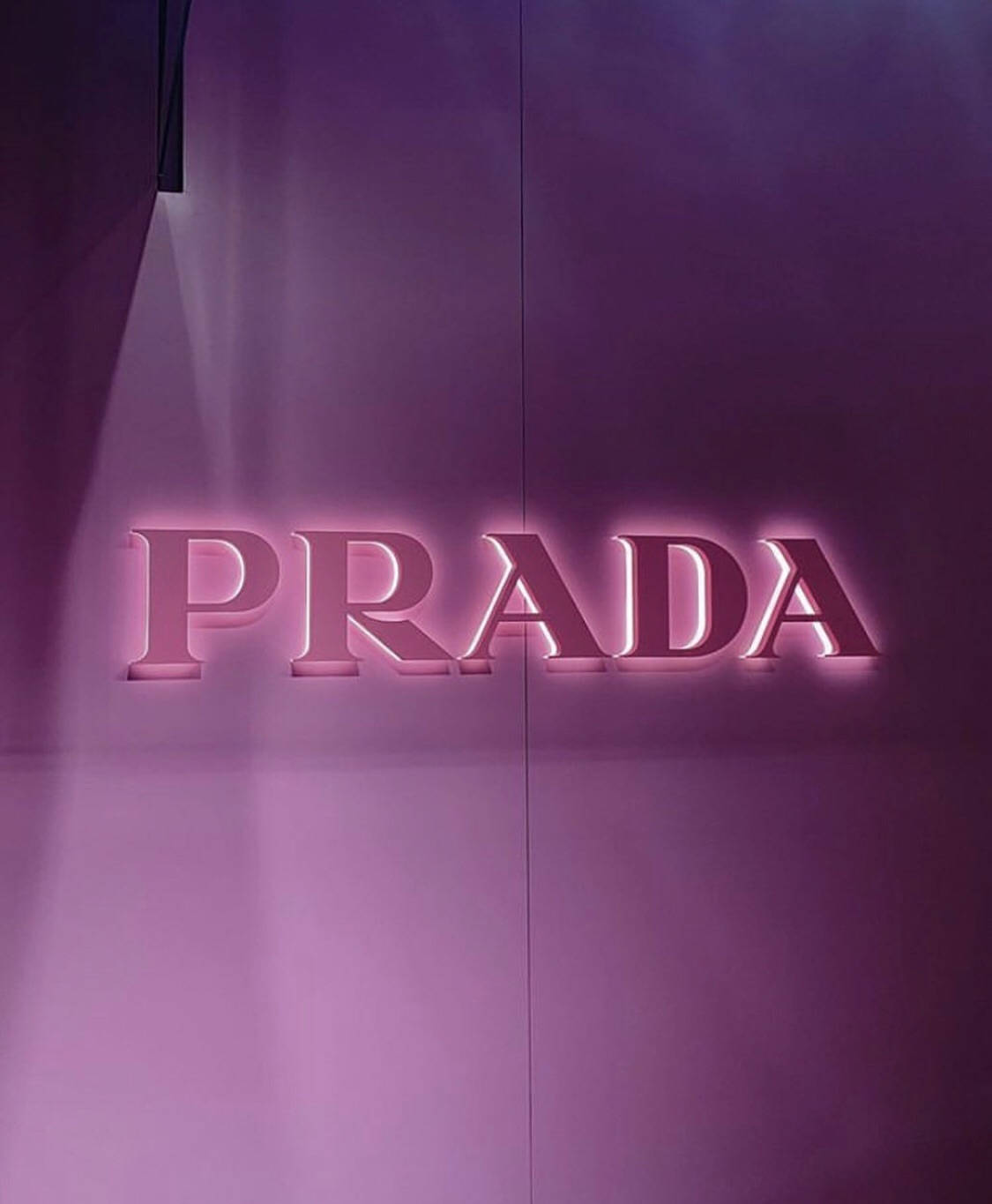 Prada標誌在紫色牆壁上以粉紅色照亮。
