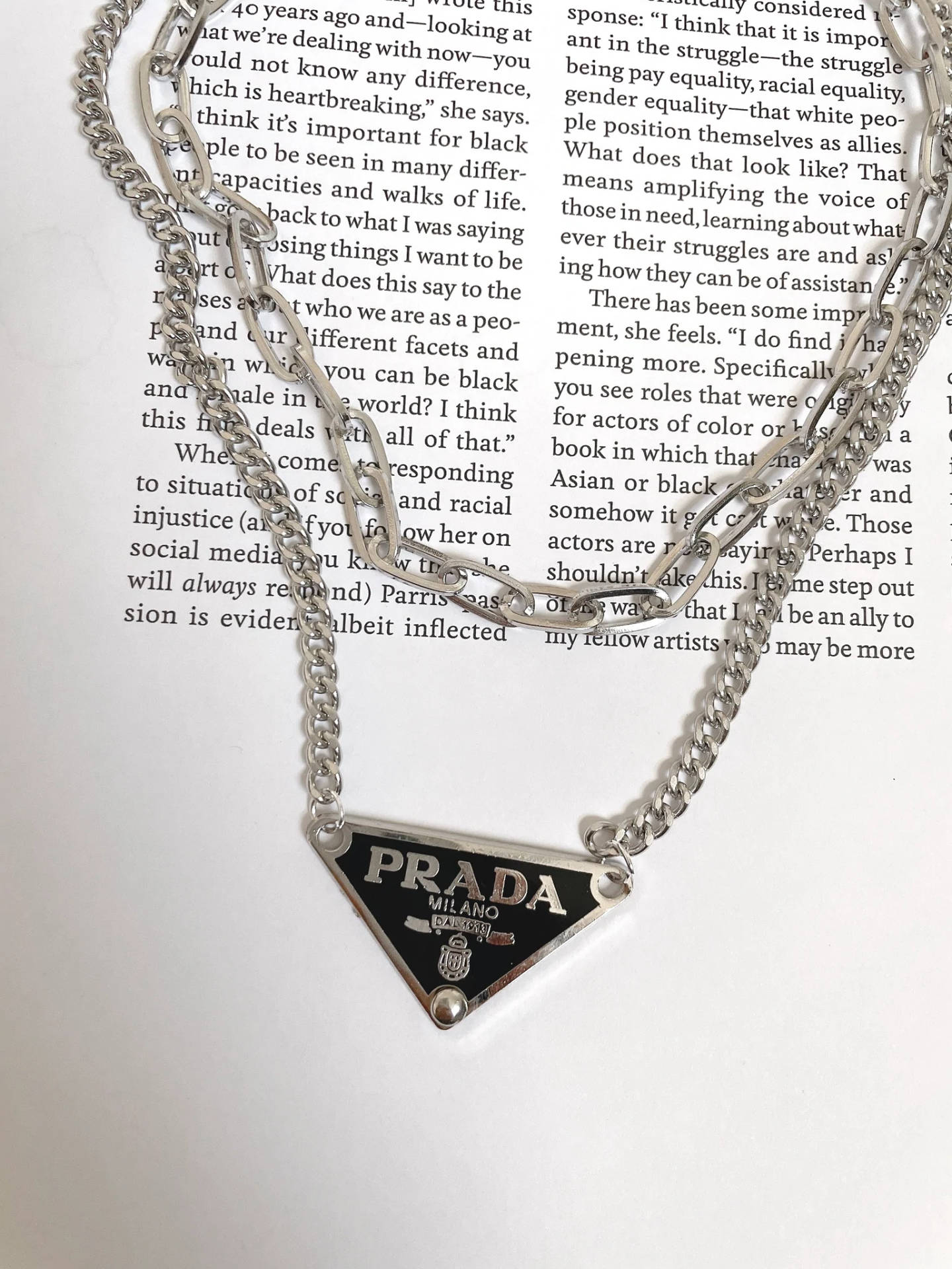 銀色 Prada 項鍊放在印有文字的打開書頁上