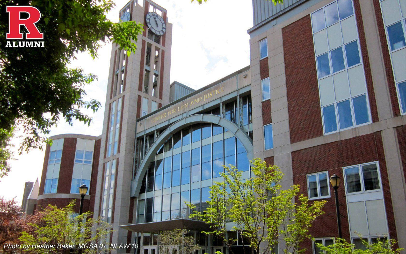 prestigious 羅格斯法學院大樓 壁紙 — 一座現代磚砌大學建築，設有鐘樓和玻璃拱門，周圍綠樹成蔭，天空明亮。