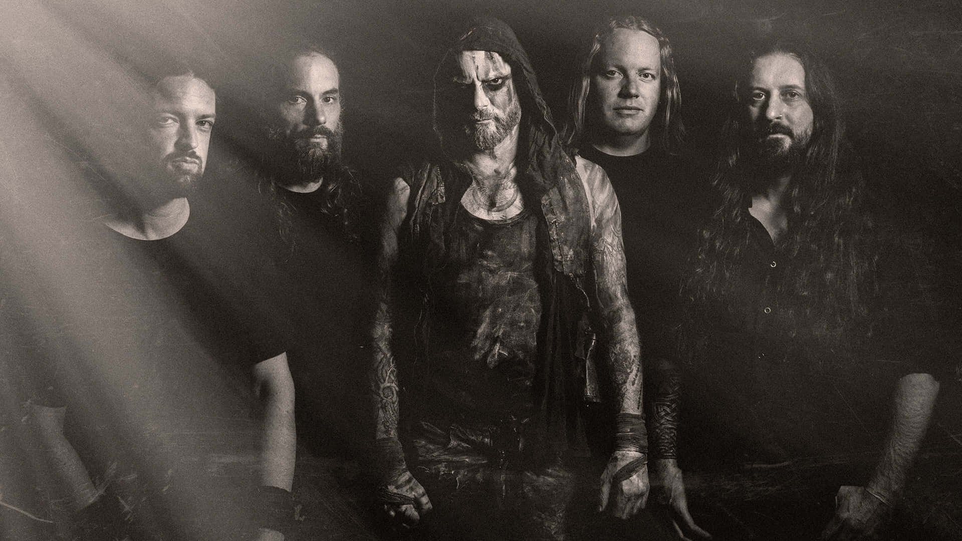 Primordial 樂隊成員 壁紙 — 五位留鬍鬚、有紋身、身穿深色衣服的男子，在戲劇性燈光的黑白攝影棚照中，營造出陰鬱氛圍。
