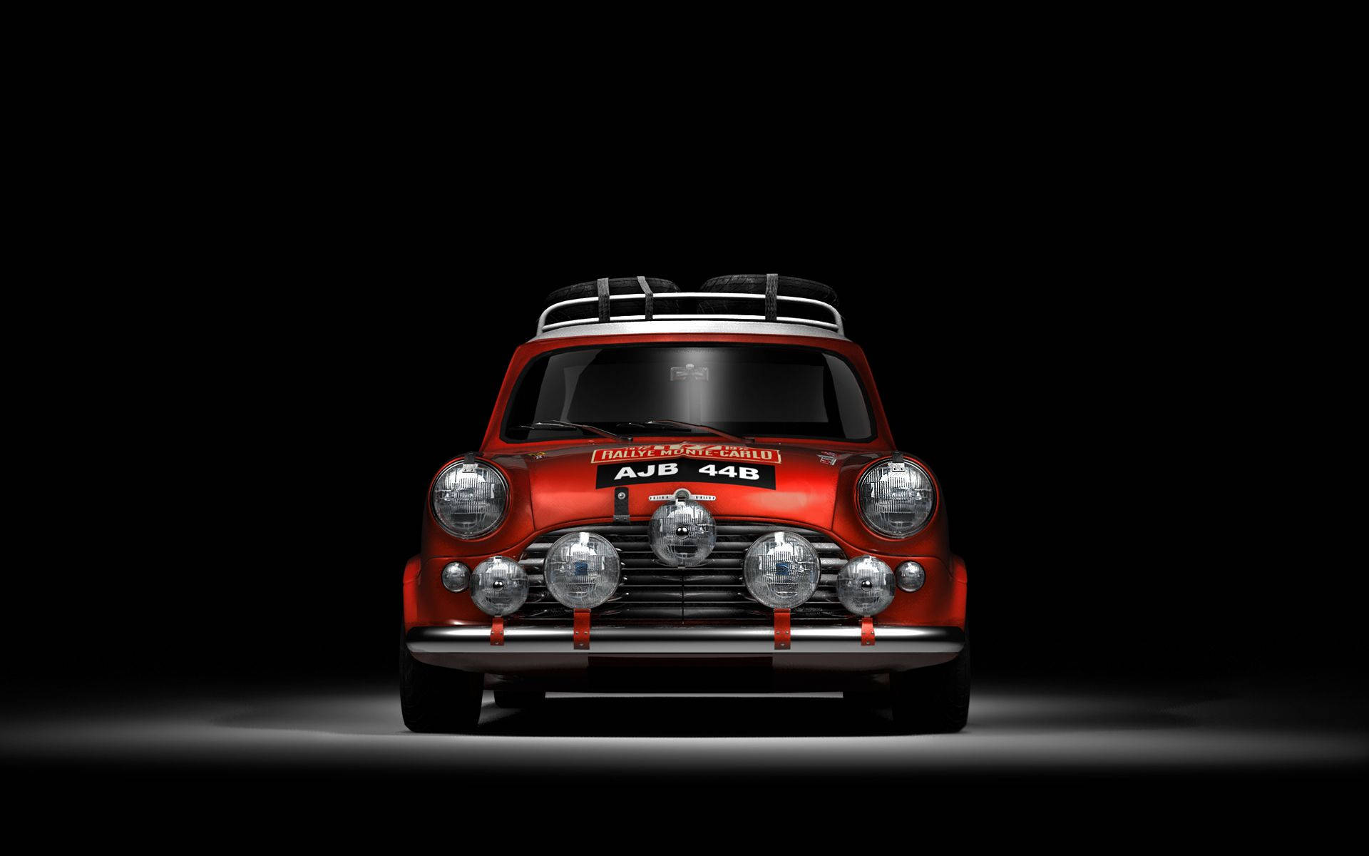 Pristine Morris Mini Cooper Classic Car 壁紙 — 一輛復古紅色拉力賽車，配有車頂行李架和多個頭燈，在黑色背景下被戲劇性地照亮。