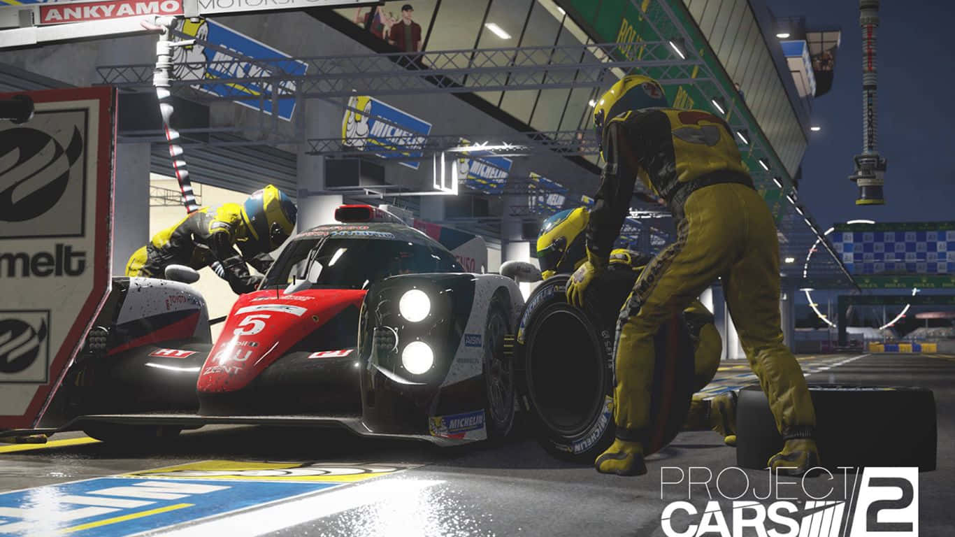 令人著迷的 Project Cars 2 遊戲背景 壁紙 — 賽車維修站團隊身穿黃色工作服，在明亮的車庫燈光下迅速更換一輛時尚紅黑賽車的輪胎。