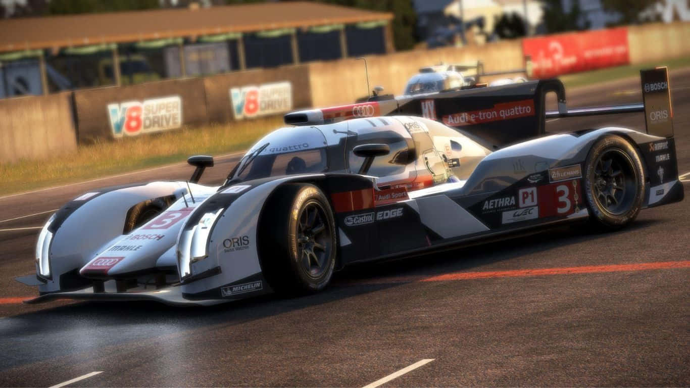 Project Cars 2 奧迪 R18 e-tron Quattro 背景 壁紙 — 一架流線型銀黑色奧迪 R18 e-tron quattro 賽車在陽光明媚的賽道上疾馳，後面緊隨另一輛車。