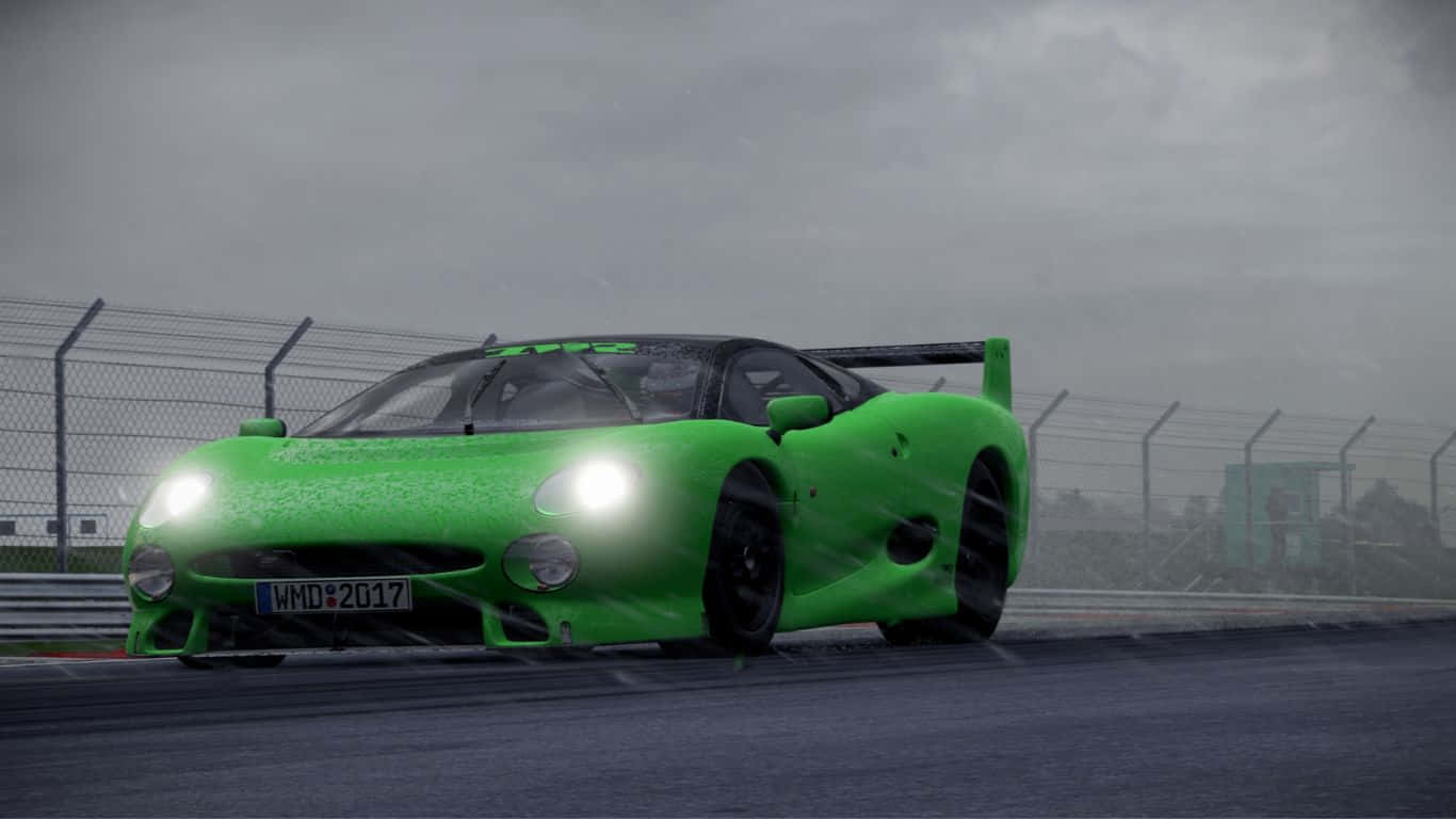 Project Cars 2 賈古拉 XJ220S TWR 背景 壁紙 — 一輛充滿活力的綠色賽車在灰色陰天底下，亮著車頭燈在濕滑的賽道上飛馳。