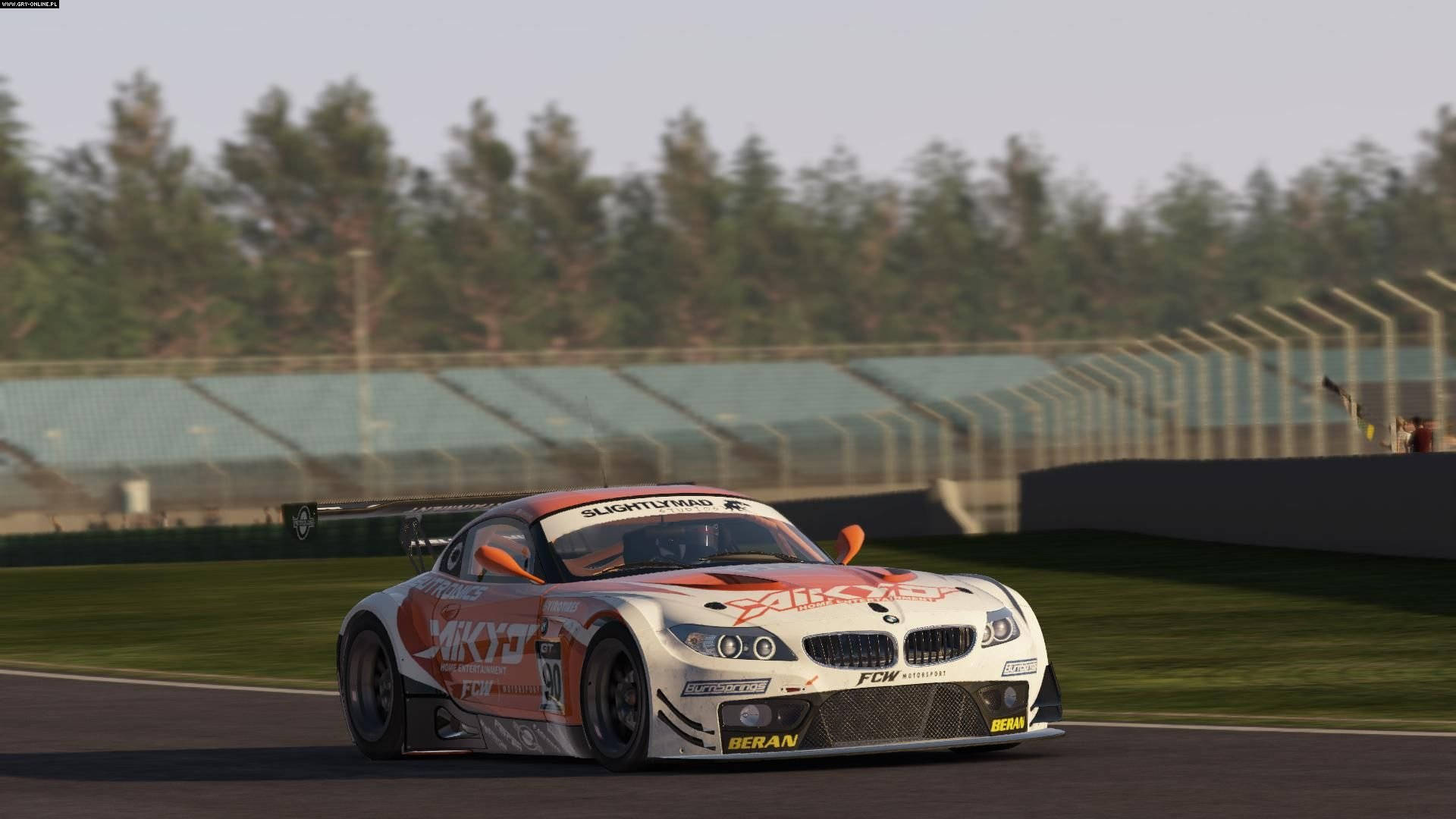 Project Cars 4K 宝马拉力賽車 壁紙 — 一輛白色和橙色的BMW賽車在賽道上飛馳，背景是綠樹和空無一人的看台。