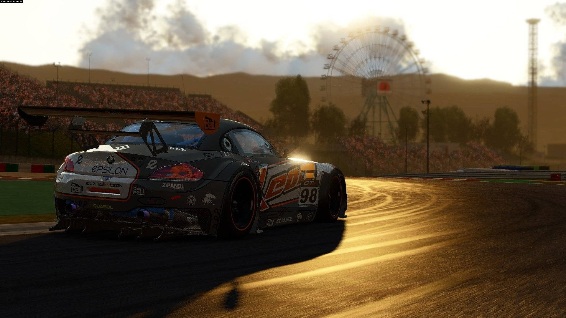 Project Cars 4K 定製寶馬 壁紙 — 一輛編號98的賽車在陽光明媚的賽道上飄移，朦朧的背景中可見摩天輪。