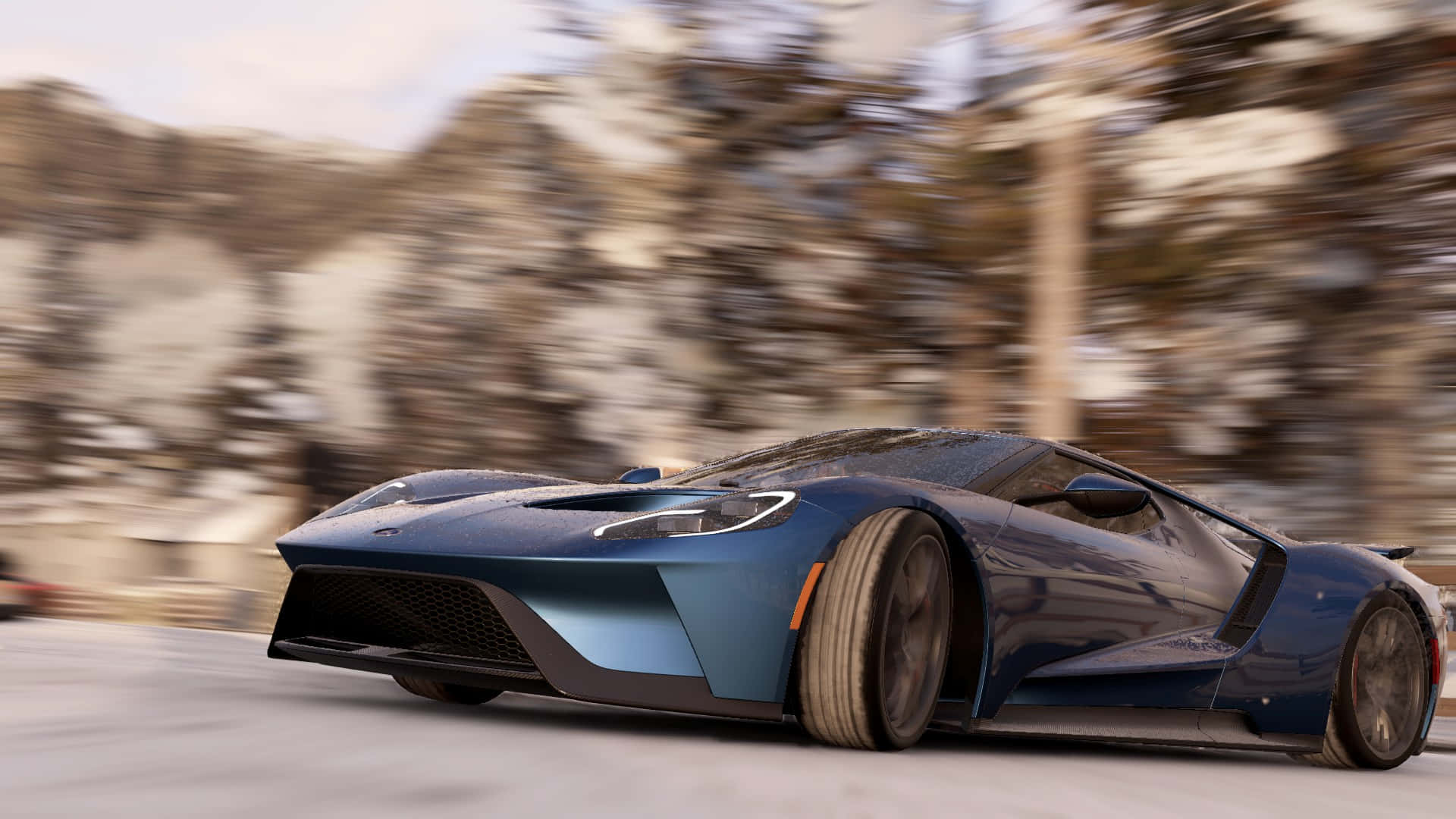 《Project Cars》藍色福特GT 高畫質背景 壁紙 — 一輛流線型藍色福特GT在積雪的山路上飛馳，背景是模糊的冬季樹木和岩石。