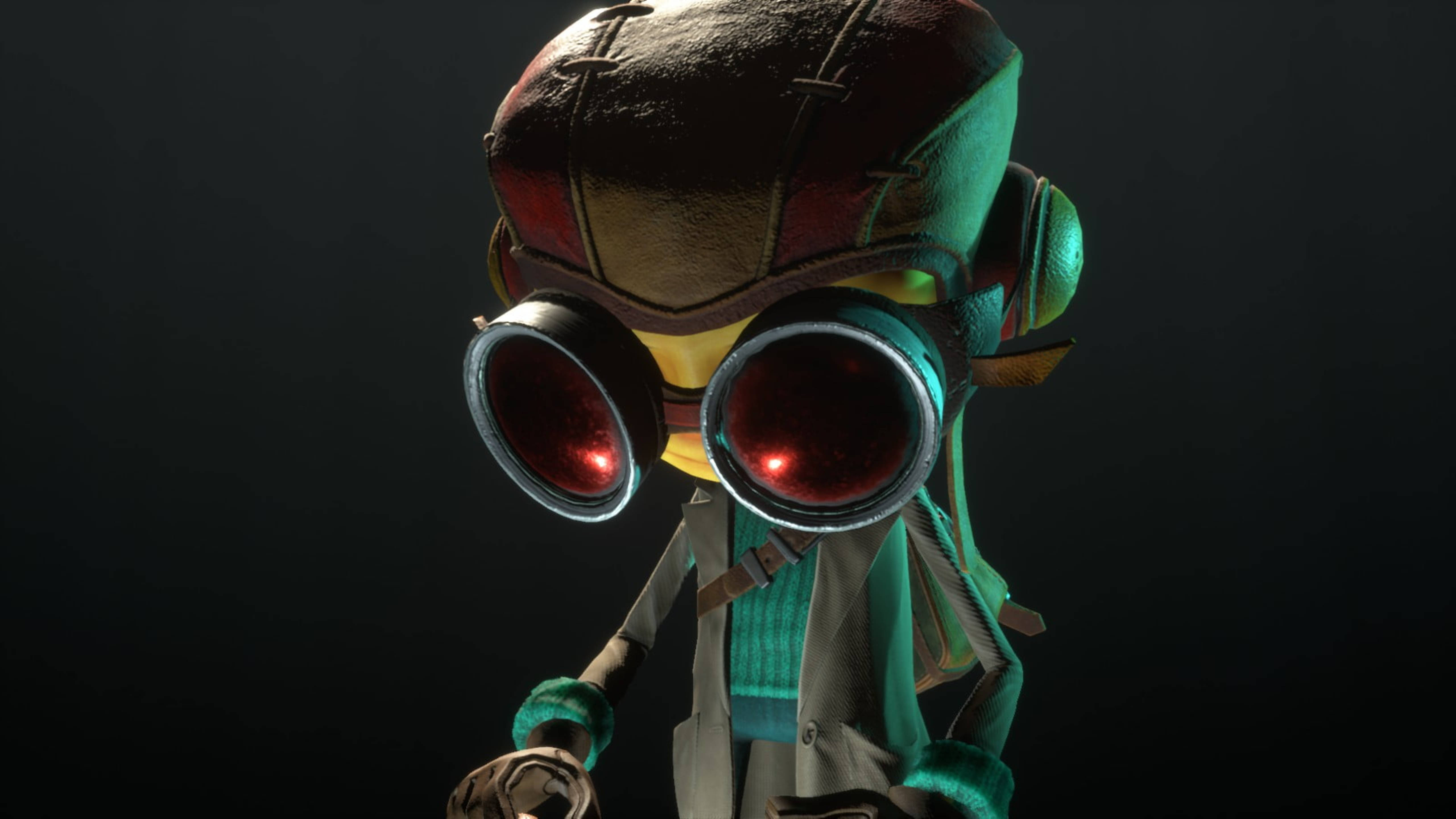 Psychonauts 遊戲英雄 Raz 壁紙 — 一個風格化的角色，戴著發光的紅色護目鏡和一個有補丁的頭盔，站在黑暗的背景前。
