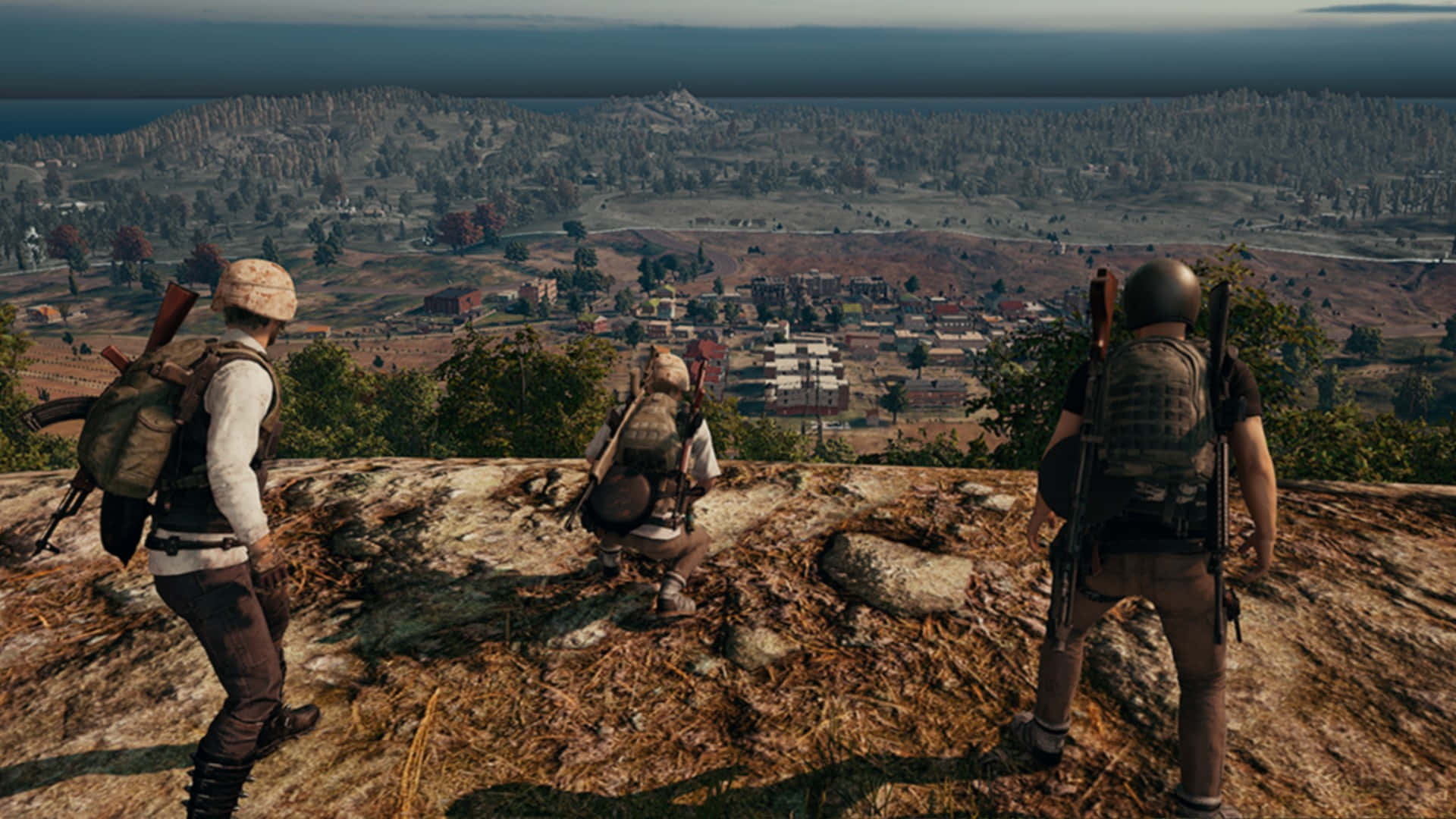 三名玩家 PUBG 1920x1080 壁紙 — 三名身穿戰術裝備的武裝玩家在一個大逃殺遊戲中，從岩石山頂俯瞰廣闊的鄉村景觀。